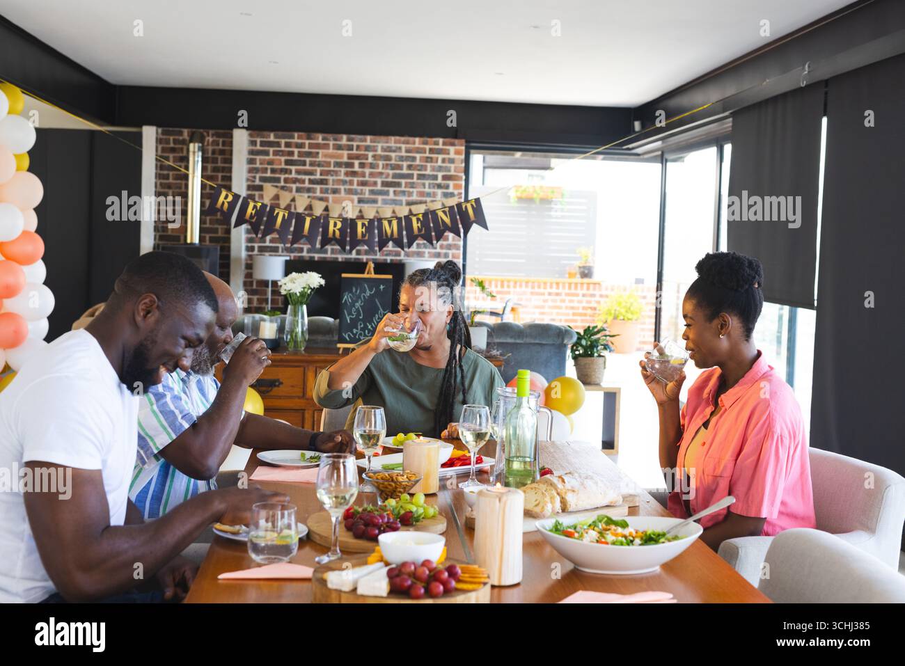 Festeggiamo la pensione a casa, gli amici condividono bevande, cibo e risate insieme Foto Stock