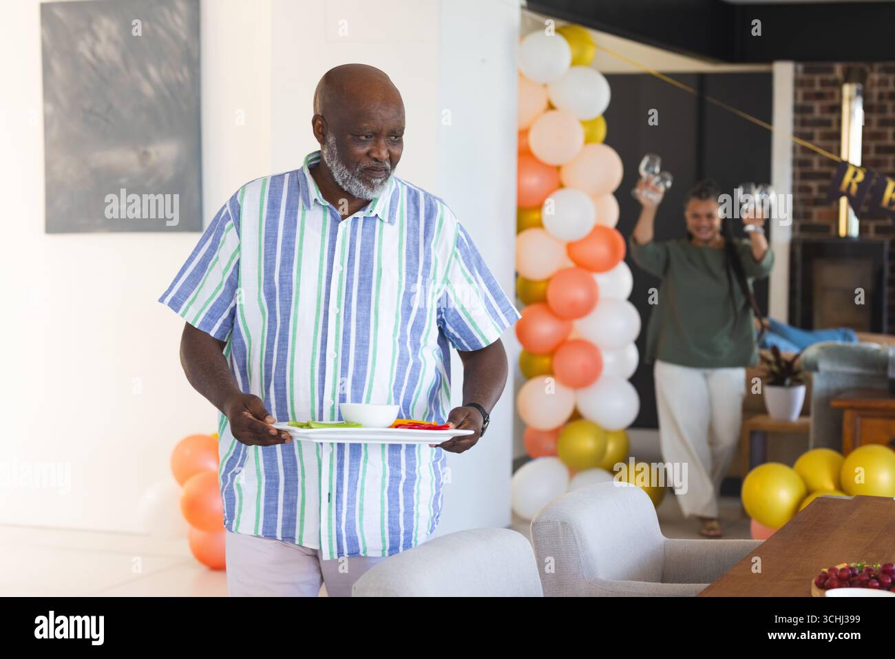 Uomo anziano che trasporta un vassoio con spuntini mentre donna tiene gli occhiali sullo sfondo Foto Stock