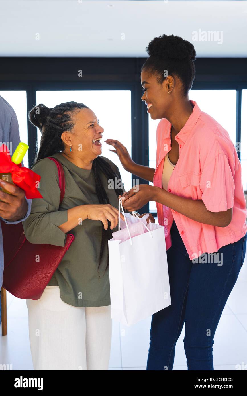 Donne sorridenti che si scambiano regali a casa, celebrano momenti di gioia insieme Foto Stock