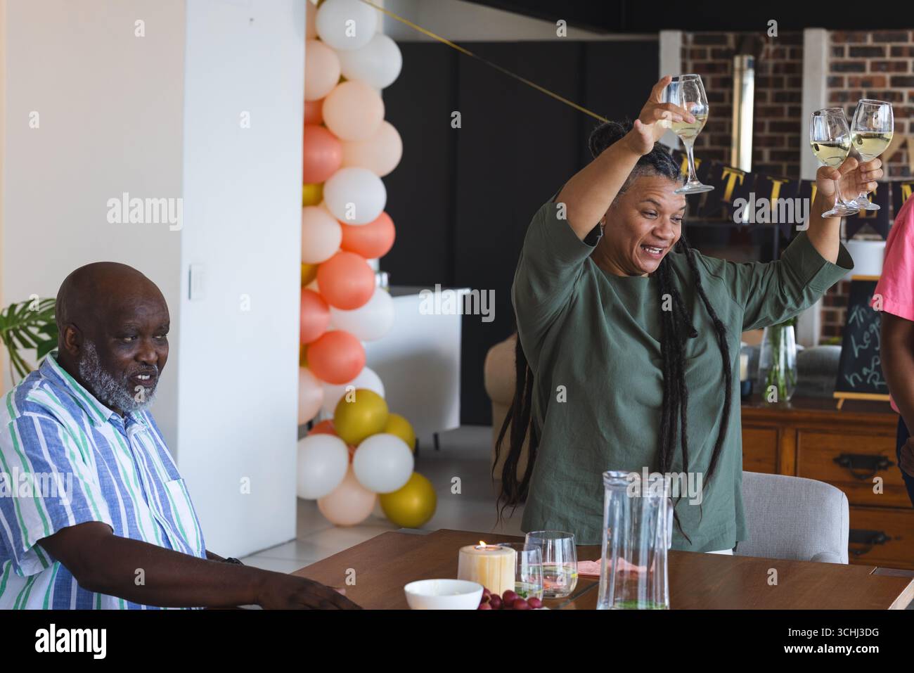 Donna gioiosa che porta i bicchieri da vino in festa a casa con gli amici Foto Stock