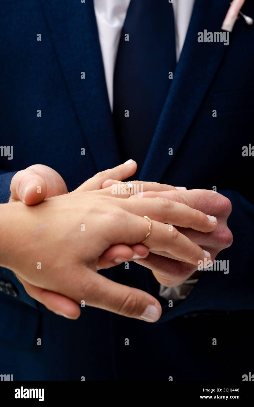 Coppia che si scambia gli anelli durante la cerimonia di nozze, tenendosi per mano e mostrando amore Foto Stock