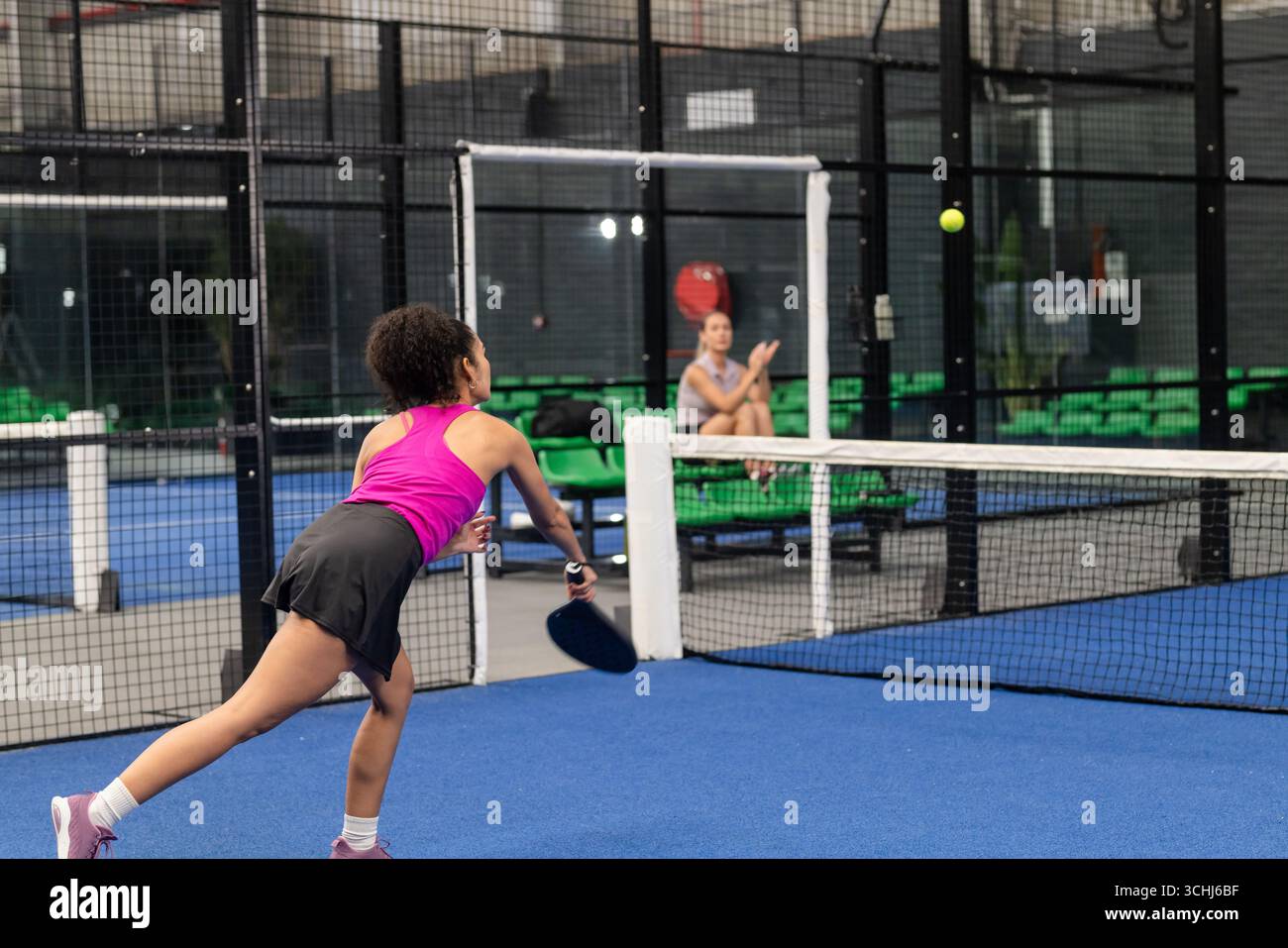Diverse compagne di squadra che si allenano con la palla gialla e la pagaia sul campo blu Foto Stock