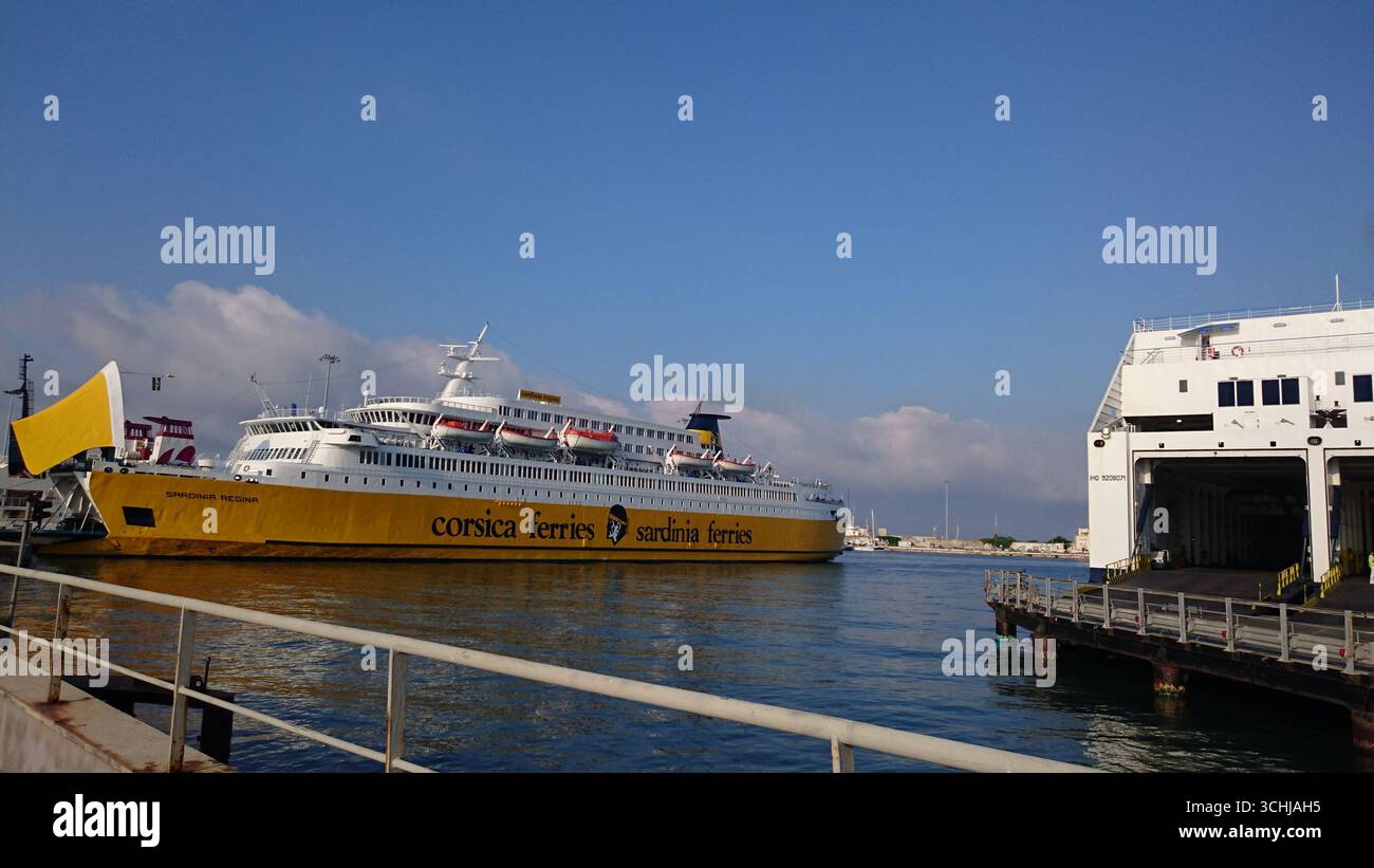 Vista del traghetto auto bianco-giallo Sardinia Regina, Corsica Ferries, Sardinia Ferries con vano aperto per auto nel porto. Mattina Foto Stock