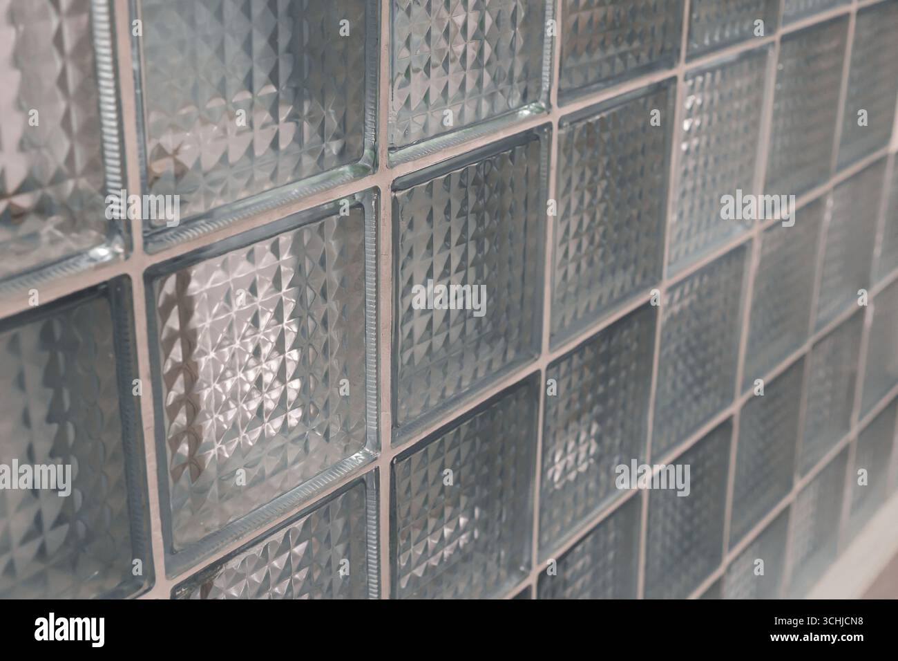 Una vista ravvicinata mostra un gruppo di blocchi di vetro trasparente disposti in una griglia, con motivi geometrici che catturano e rifrangono la luce, migliorando Foto Stock