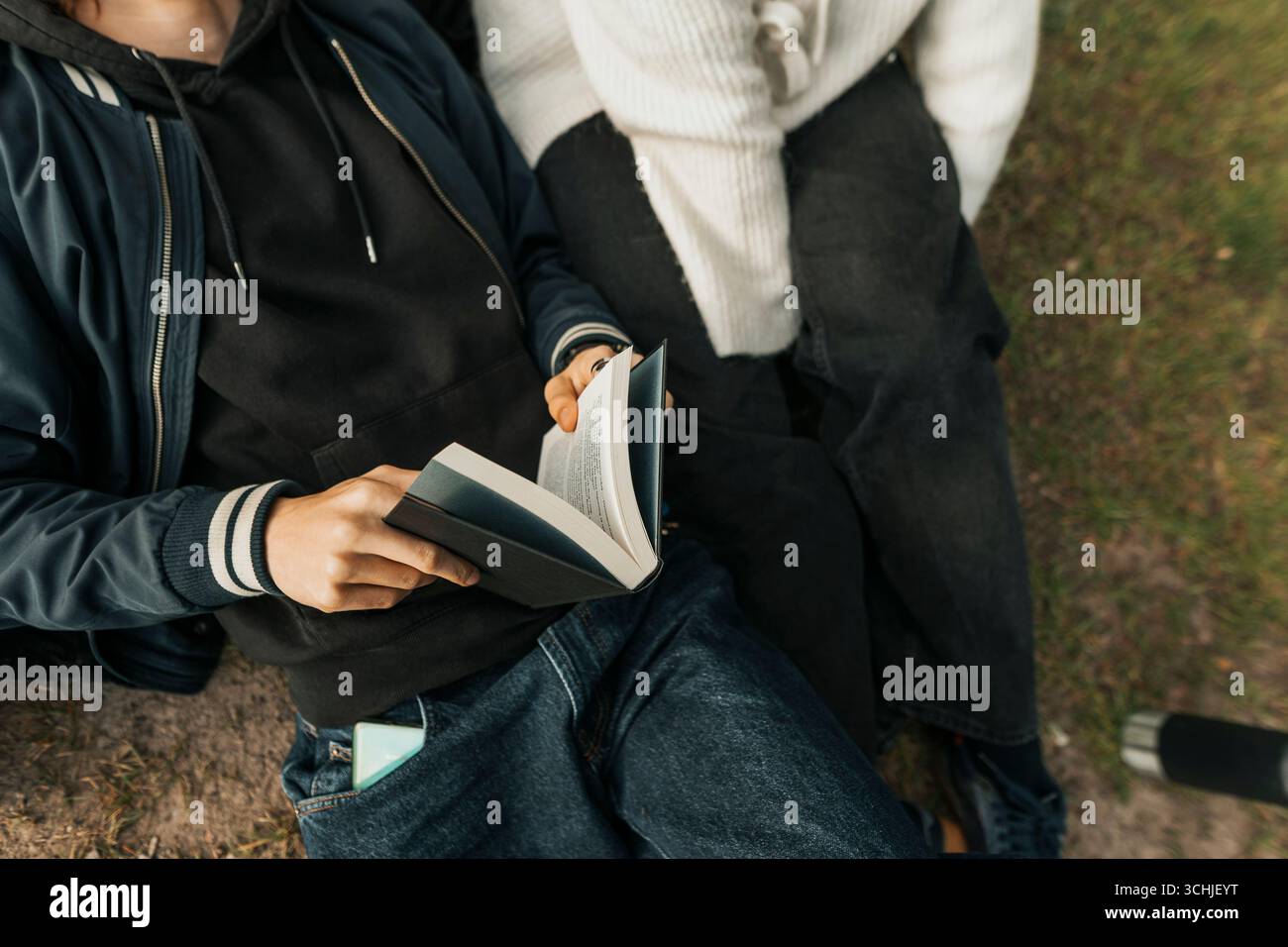 Sezione centrale ad alto angolo di un giovane che tiene un libro a fianco di un'amica Foto Stock