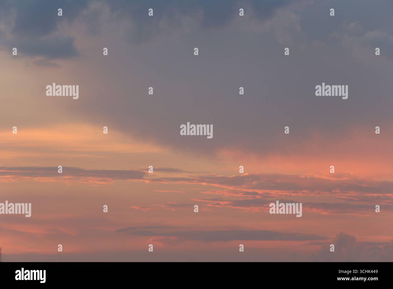 Cattura l'incantevole bellezza di un tramonto con sfumature rosa e arancione che dipingono il cielo, creando un'atmosfera serena e tranquilla sulle nuvole. Foto Stock