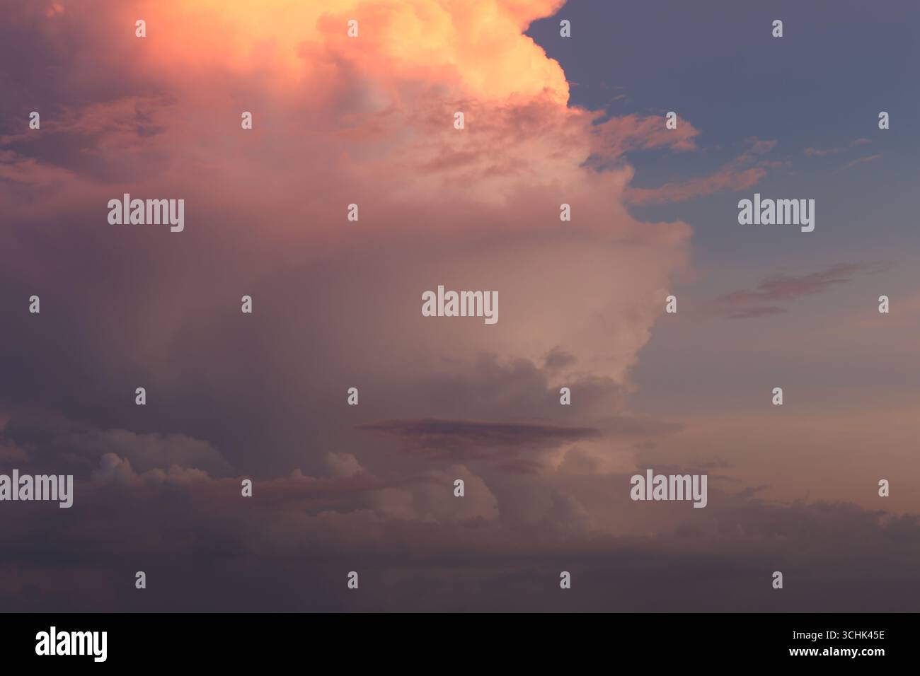 Una splendida vista di un tramonto caratterizzato da spettacolari nuvole illuminate da calde sfumature di rosa e arancione, creando un'atmosfera serena. Foto Stock