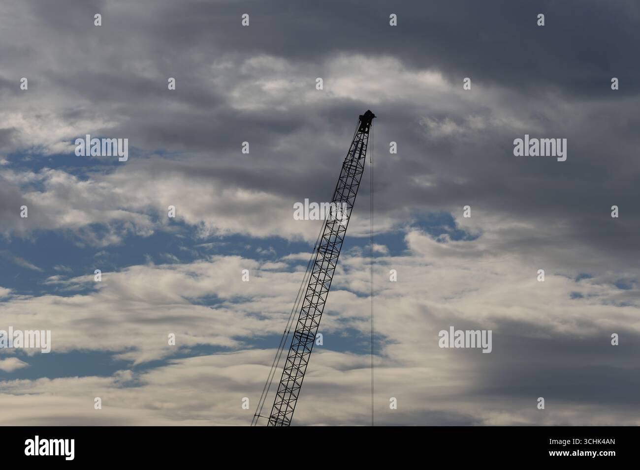 Una gru alta si erge su uno sfondo di nuvole spettacolari, che rappresentano l'essenza dell'edilizia e dell'industria. Foto Stock