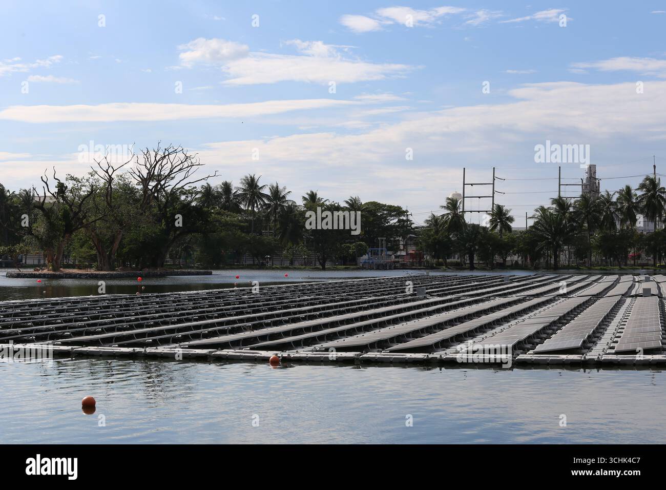 Tranquillo scenario di una fattoria di acquacoltura con zattere galleggianti e verdi lussureggianti, che si riflettono sotto un cielo parzialmente nuvoloso, ideale per la natura e l'agricoltura Foto Stock