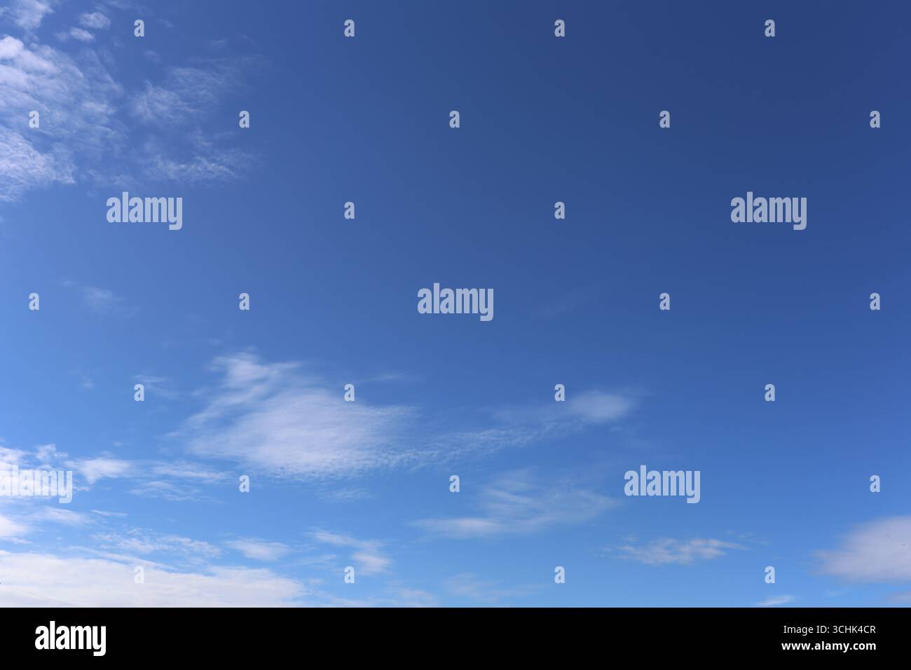 Una splendida vista su un cielo azzurro e limpido adornato da soffici nuvole, ideale per l'uso come sfondo in progetti creativi o come rappresentazione di tranquillità Foto Stock