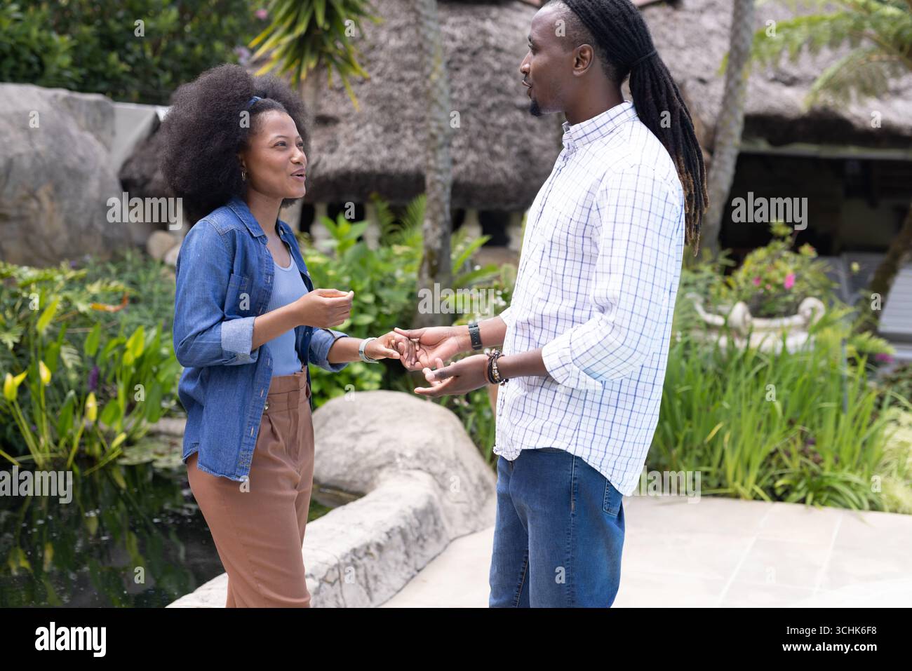 Coppia che si diverte a conversare nel lussureggiante giardino, condividendo momenti di gioia insieme Foto Stock