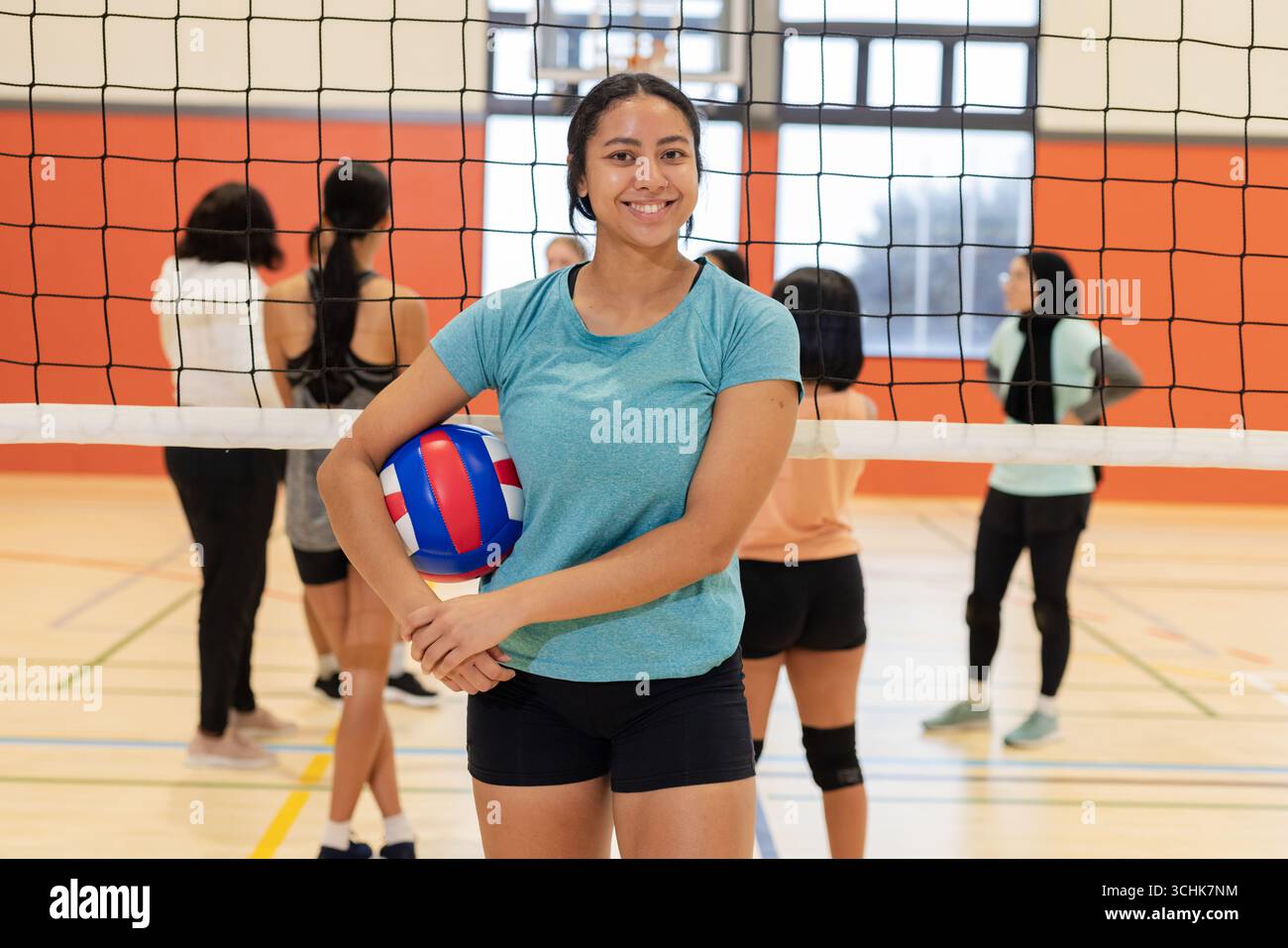 Diverse squadre femminili di pallavolo che praticano la rete con palla rosso-bianco-blu nella palestra scolastica Foto Stock