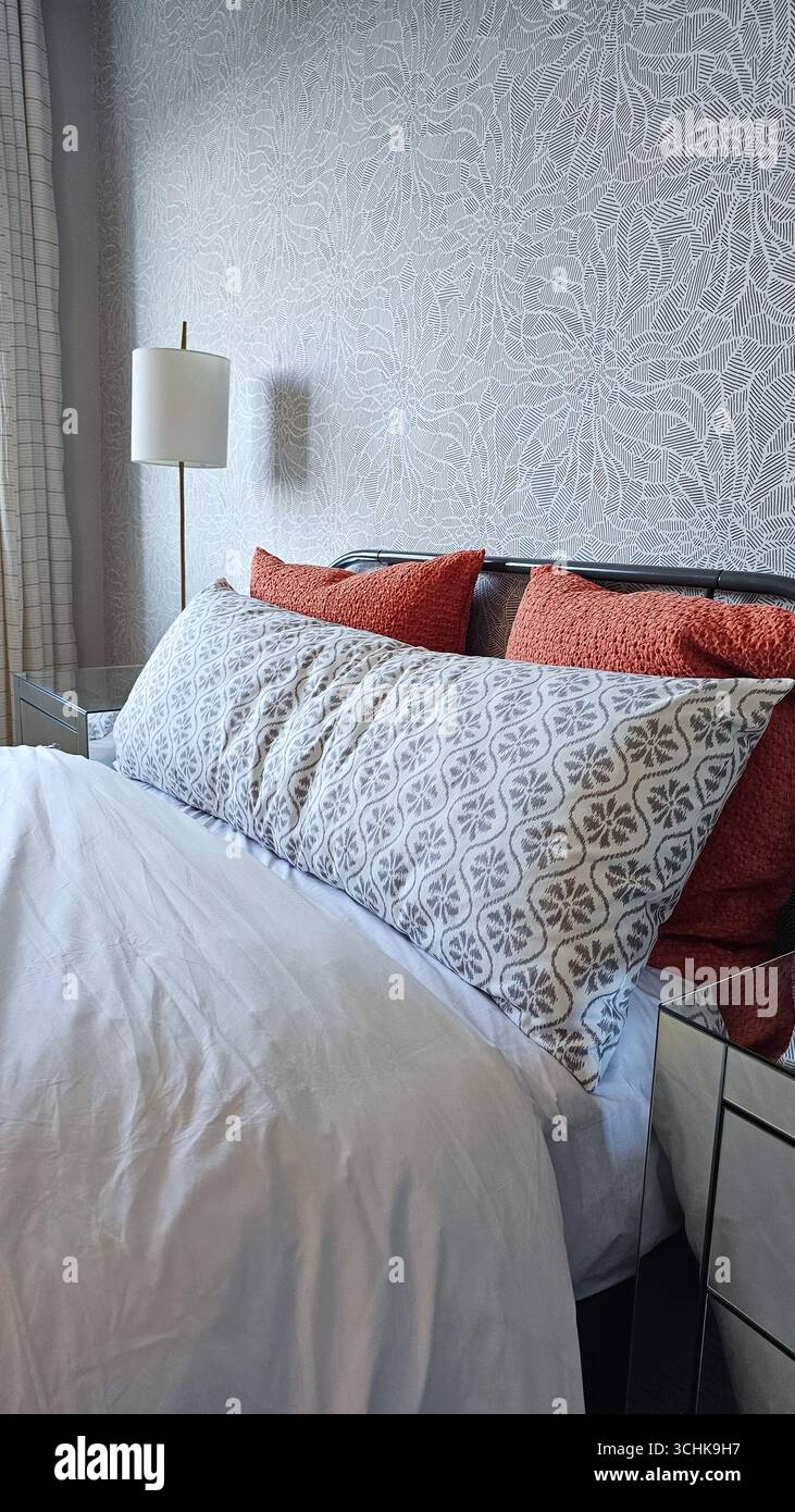 L'accogliente camera da letto presenta lussuosi letti con cuscini decorativi e una lampada elegante, che creano un'atmosfera tranquilla per momenti di riposo Foto Stock