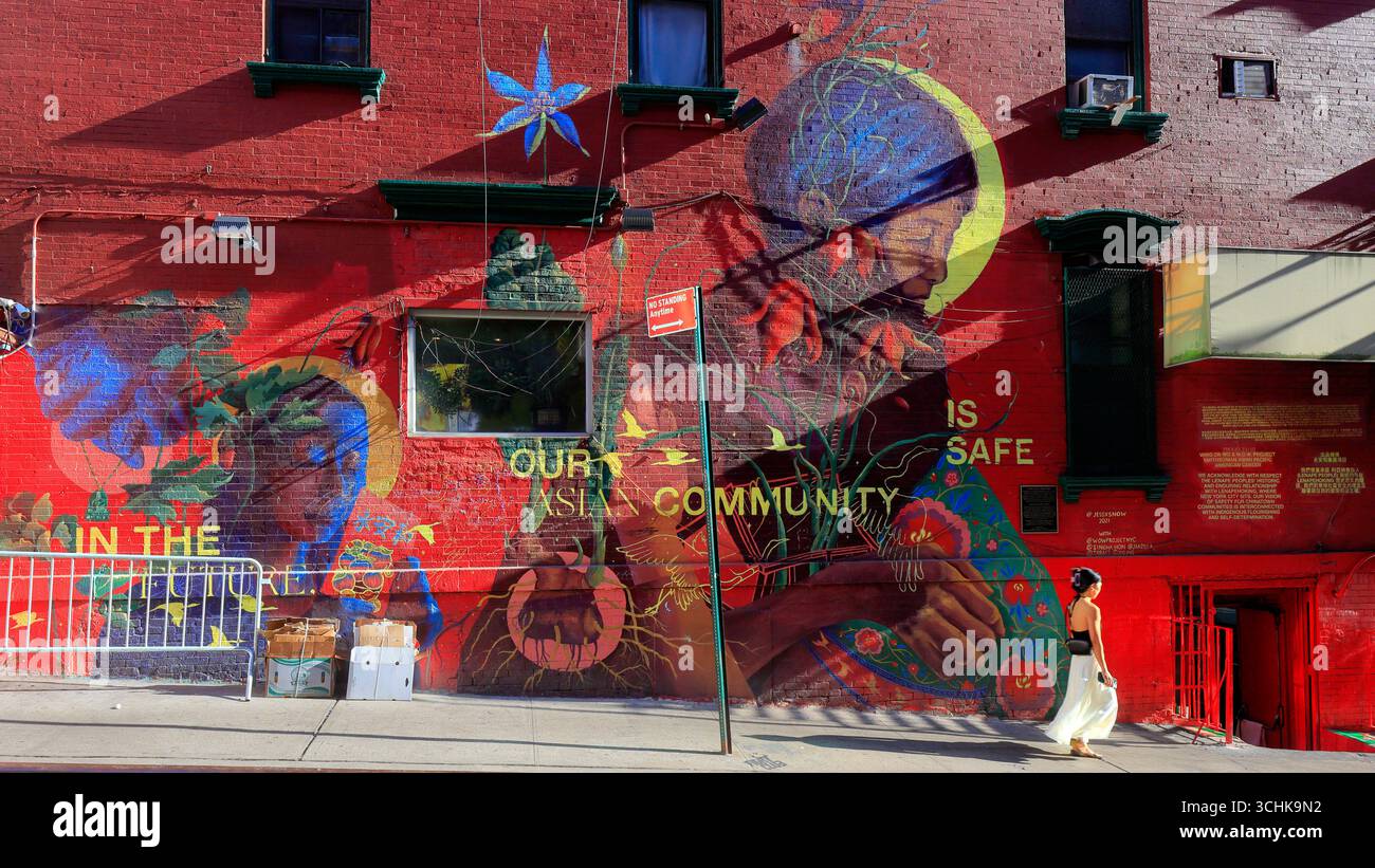 Una persona oltrepassa il murale pubblico "in futuro, la nostra comunità è al sicuro" a New York Chinatown 美國 紐約 Foto Stock