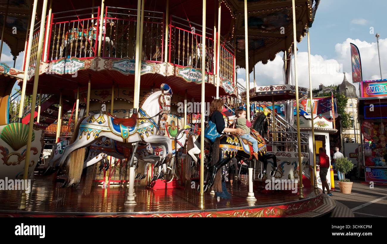 LUSSEMBURGO, EUROPA - 1 SETTEMBRE 2025 - madre e figlio si divertono a cavalcare un cavallo a giostra a Schueberfouer, la più grande fiera annuale del Lussemburgo Foto Stock