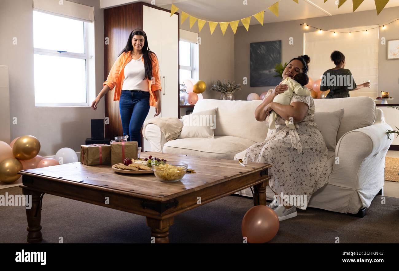 Diverse amiche che festeggiano a casa con regali, decorazioni e momenti di gioia insieme Foto Stock