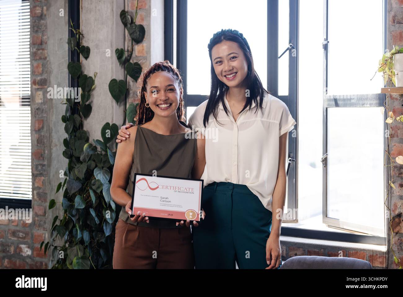 Celebrazione dei risultati ottenuti, donne diverse che detengono un certificato e sorridono in un ufficio moderno Foto Stock