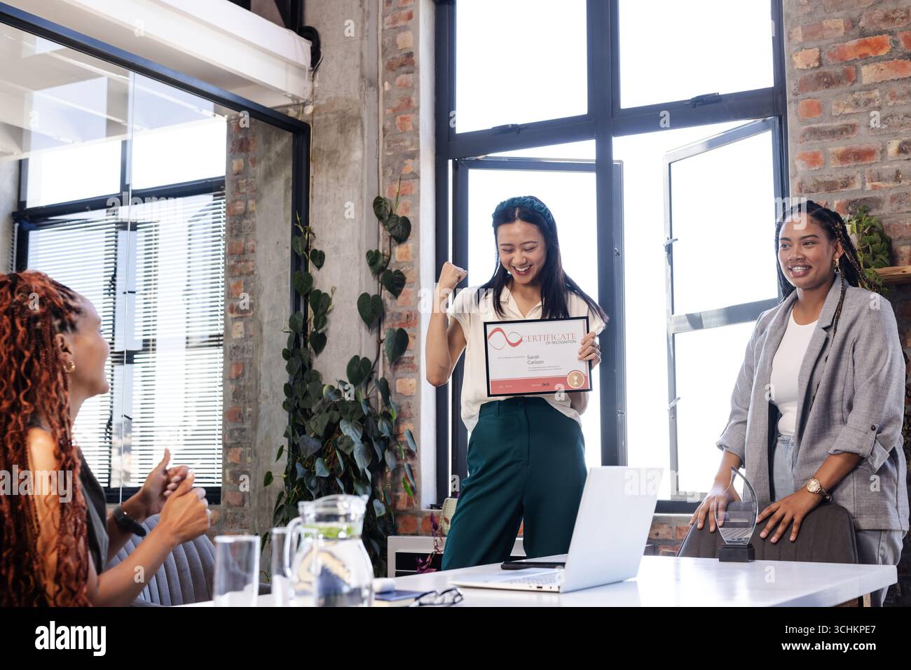 Team femminile diversificato che celebra il successo come donna detiene il certificato in un ufficio moderno Foto Stock
