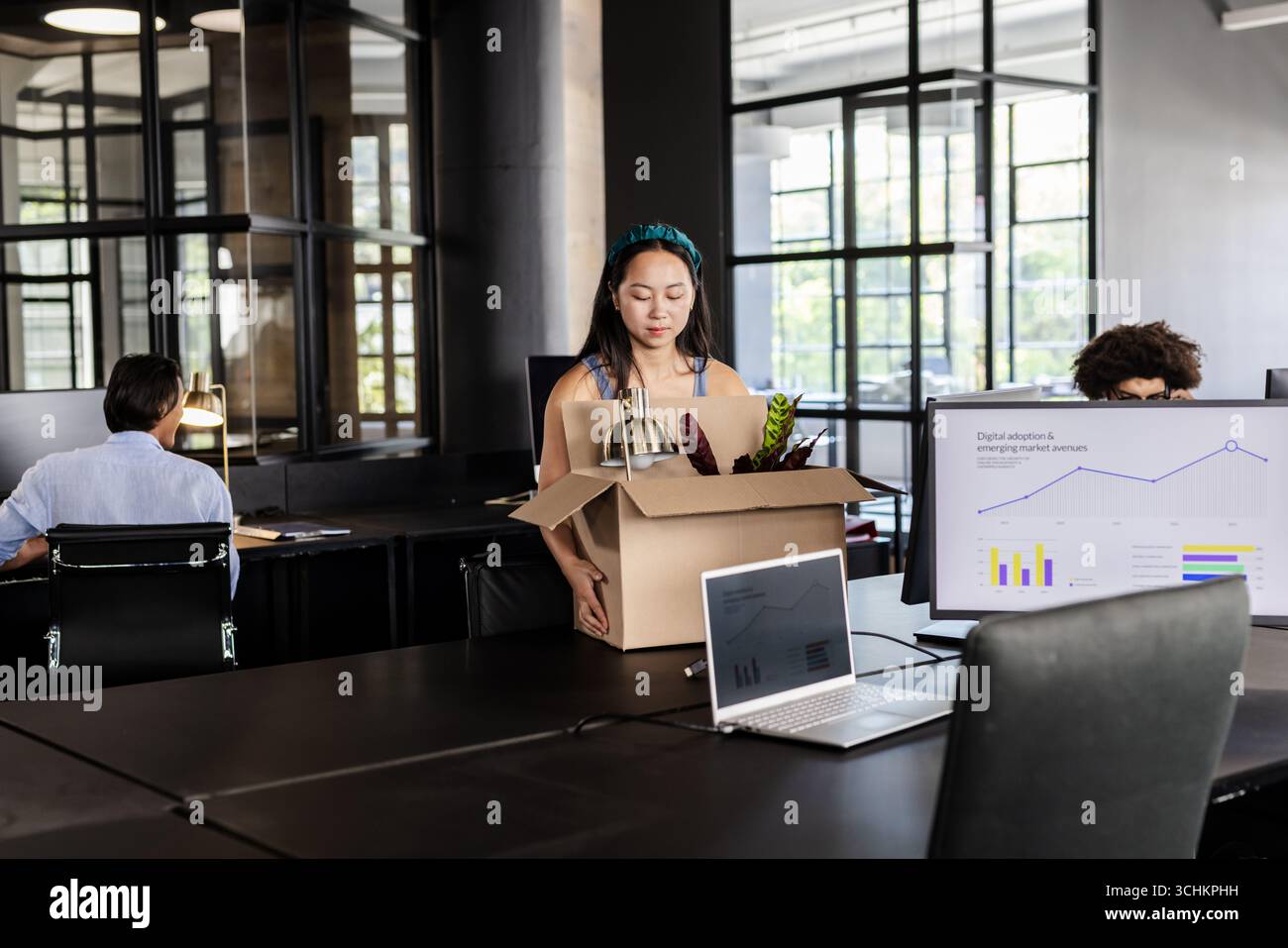Donna asiatica che trasporta una scatola con forniture per ufficio, inizia un nuovo lavoro sul posto di lavoro moderno Foto Stock