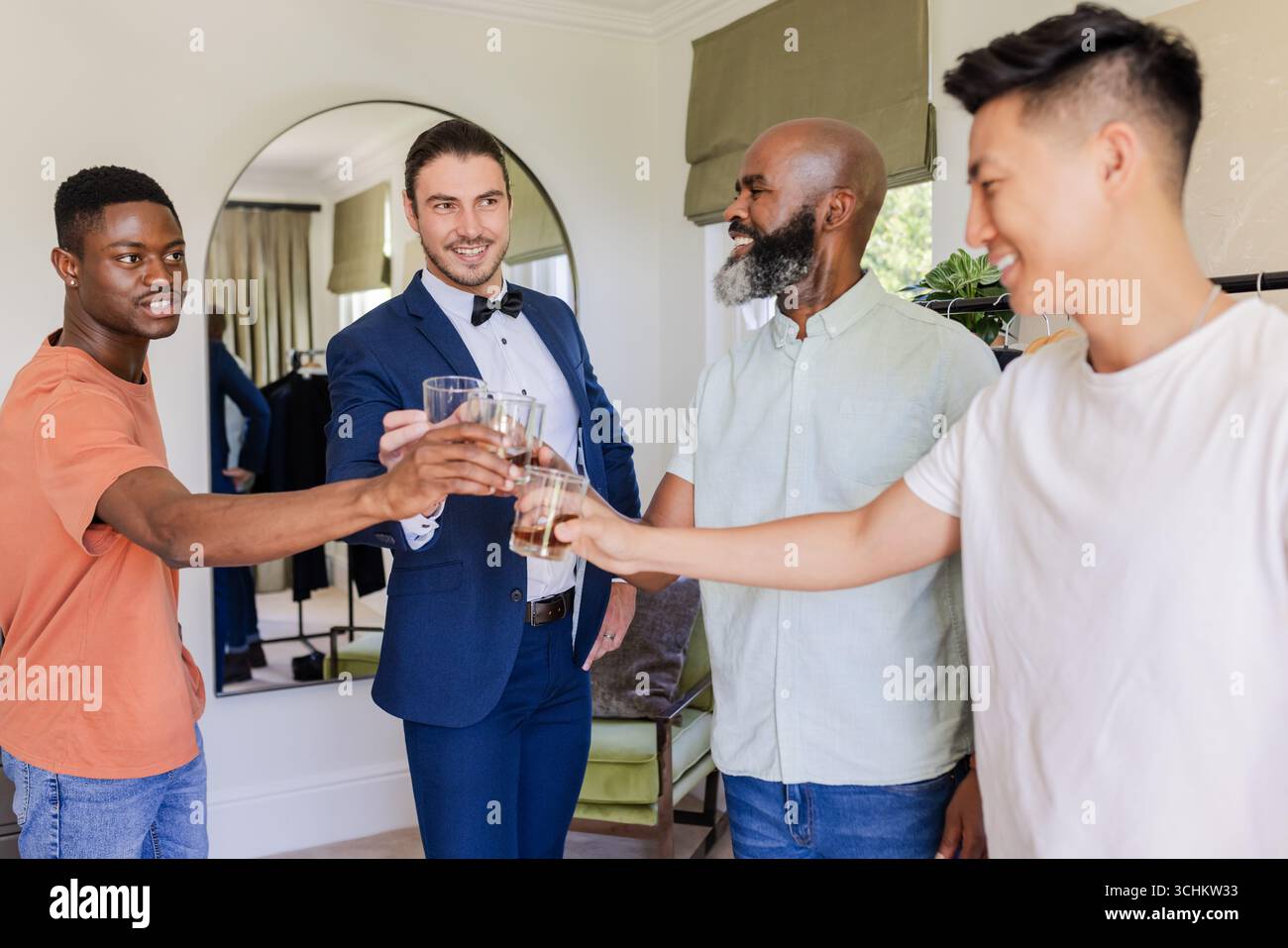 Gli amici brindano con un drink, celebrano il giorno speciale dello sposo in una camera elegante Foto Stock