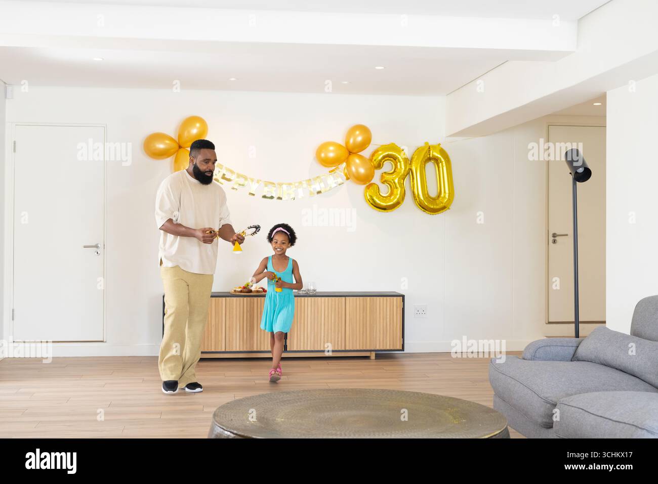 Padre e bambino festeggiano il compleanno con palloncini e decorazioni a casa Foto Stock