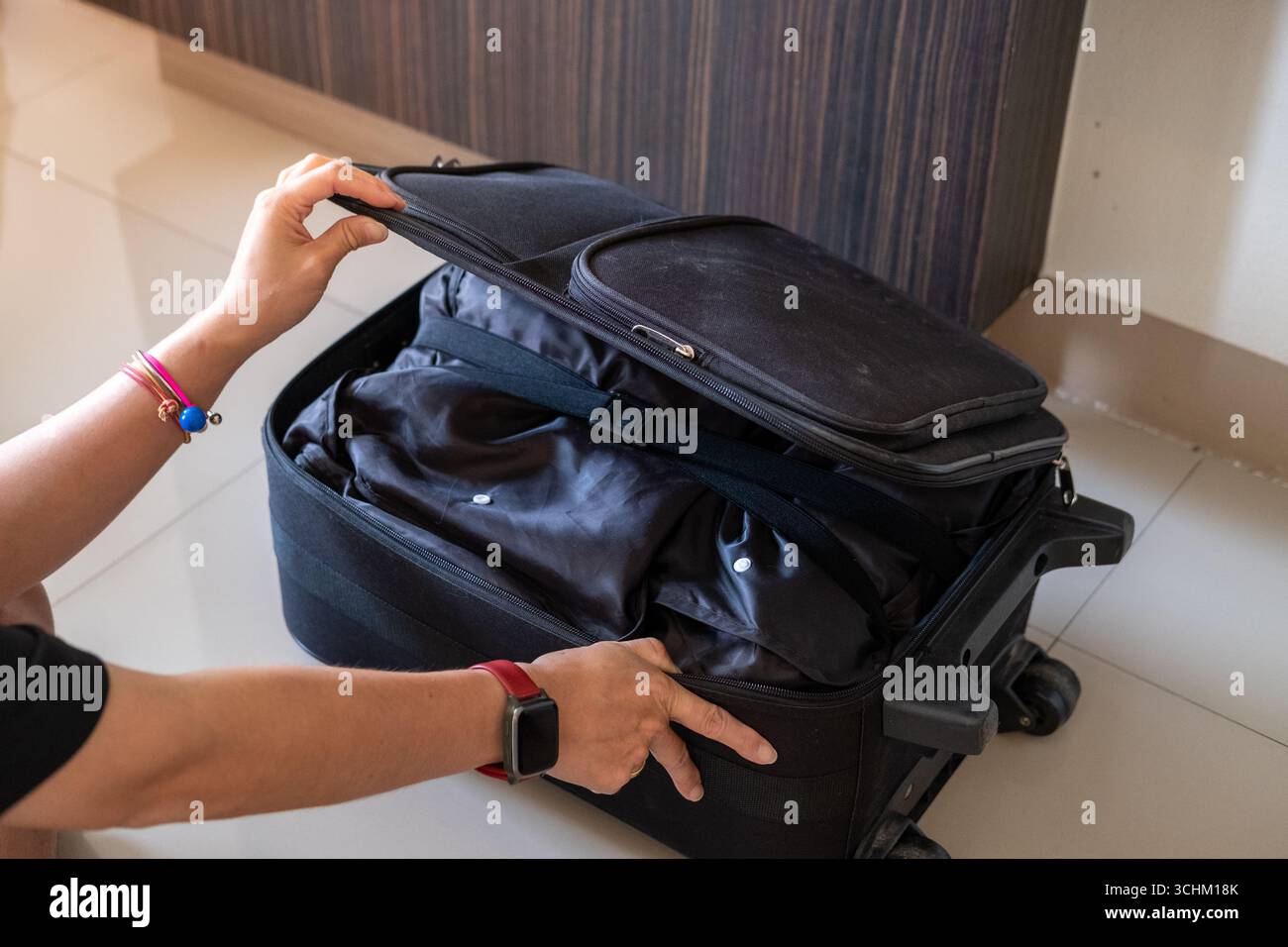 Le mani della donna confezionano con cura la valigia con vestiti e gli indispensabili per il viaggio in vacanza Foto Stock