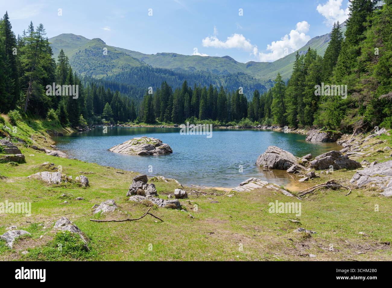 Vivace lago alpino turchese in estate, circondato da verdi montagne e foreste Foto Stock