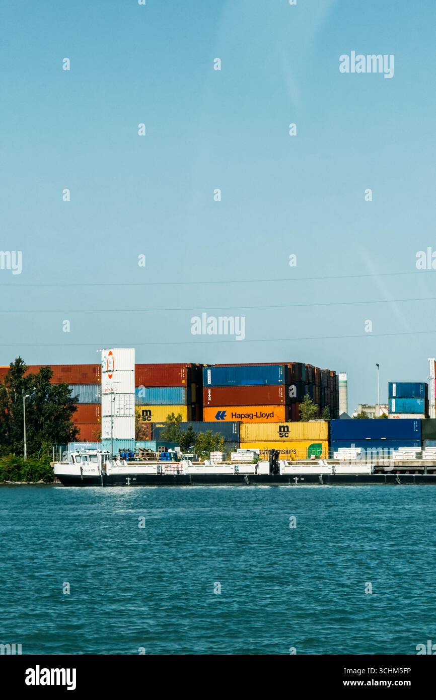 Container impilati e chiatte ancorate al Port de Lyon lungo il fiume Rodano. Lione, Francia - 19 agosto 2025 Foto Stock