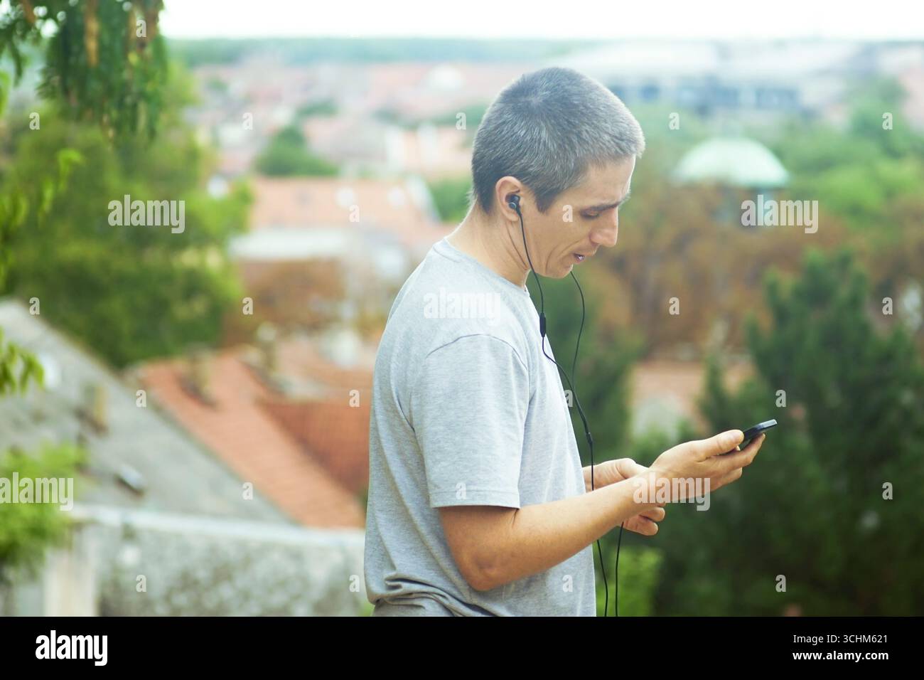 Uomo che ascolta musica con gli auricolari all'aperto, tenendo lo smartphone in mano. Concetto di stile di vita sano, motivazione fitness, ispirazione per l'allenamento Foto Stock