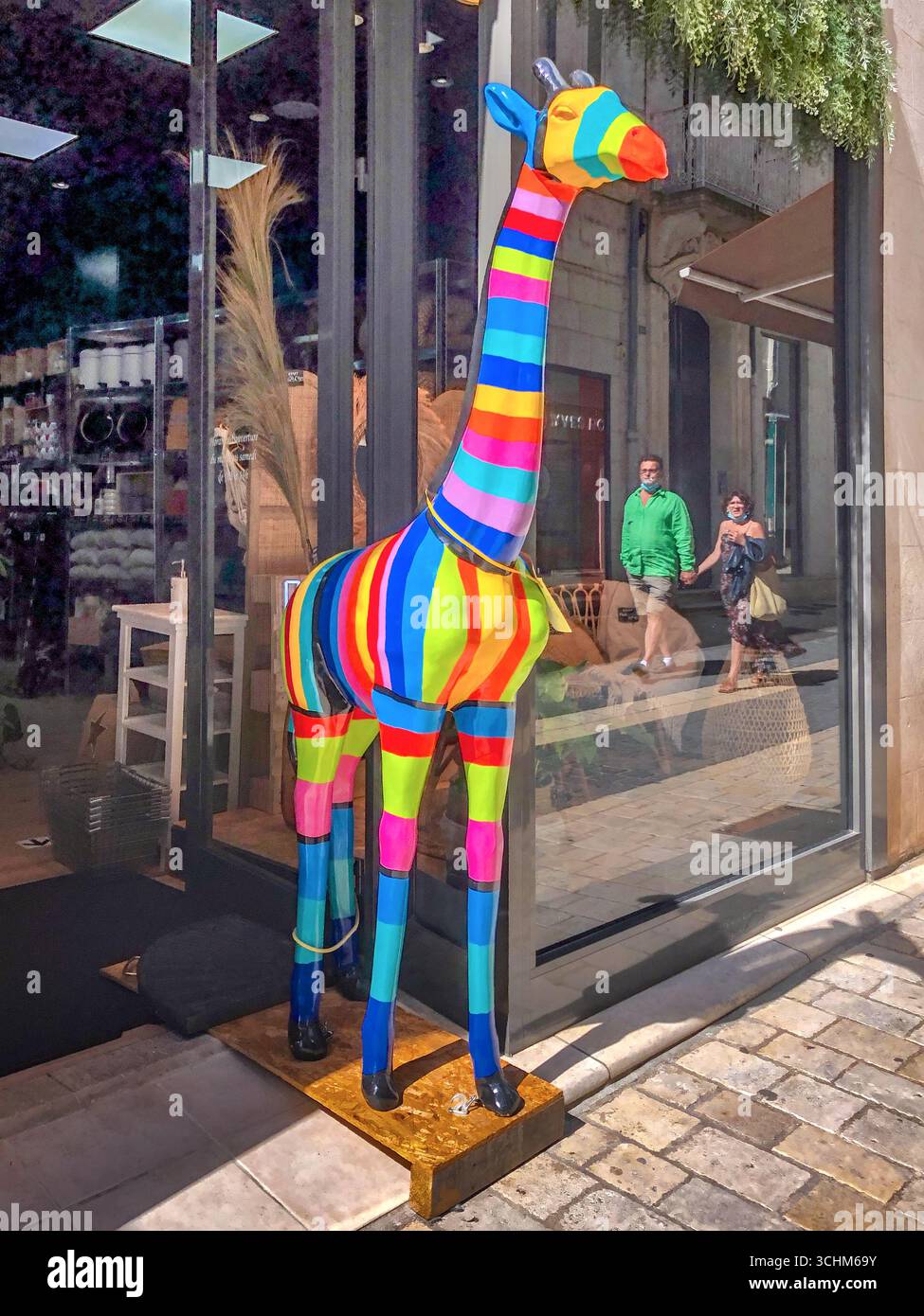 Giraffa a righe multicolore imbottita utilizzata come attraente esposizione all'ingresso del negozio - Chatellerault, Vienne (86), Francia. Foto Stock
