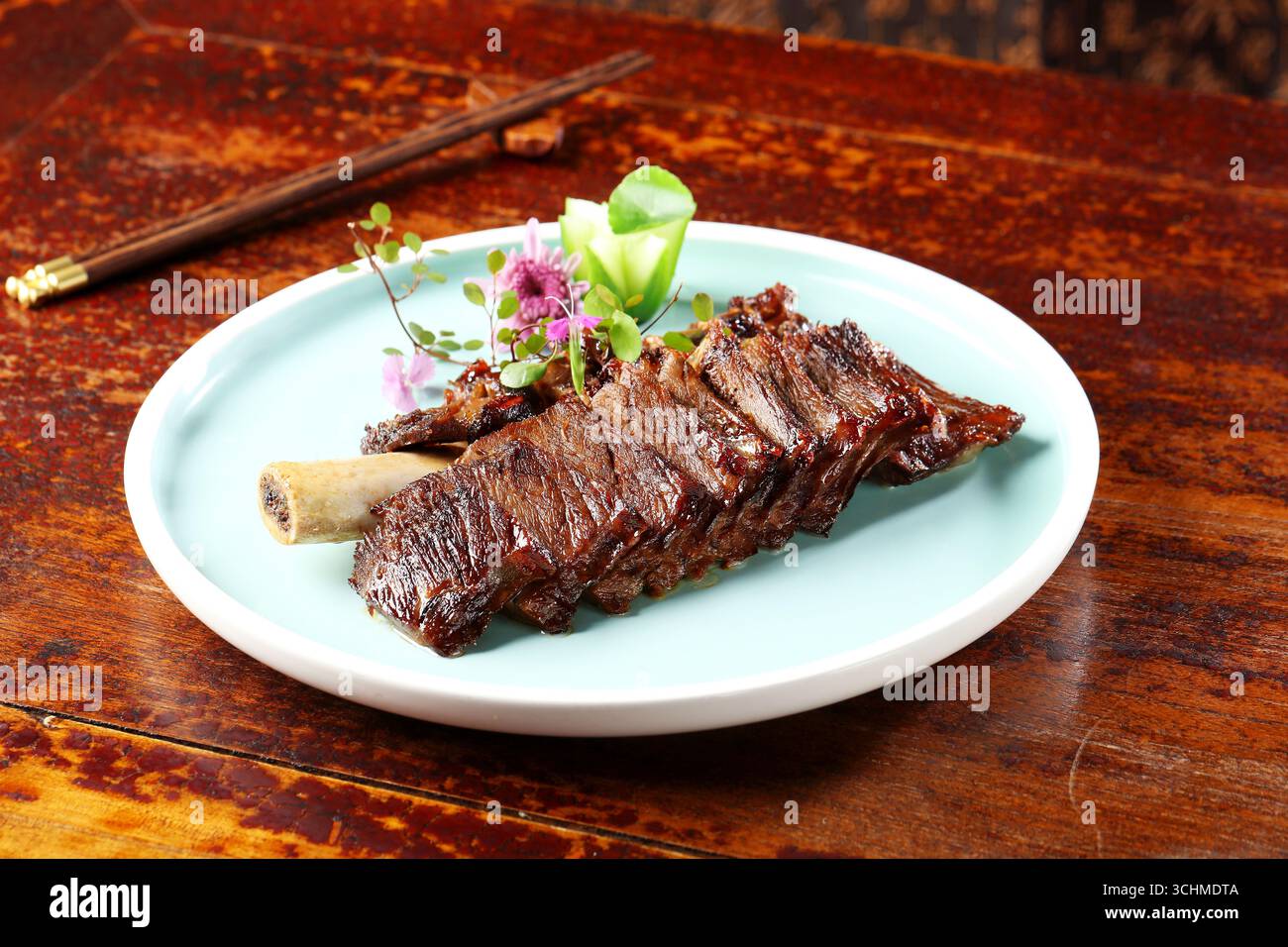Costolette di manzo ossa tagliate su piatto di acqua con fiori commestibili Foto Stock