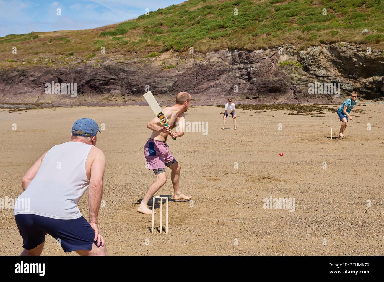 Una famiglia che gioca a cricket sulla spiaggia di Polzeath, in Cornovaglia, in una soleggiata giornata estiva. Foto Stock