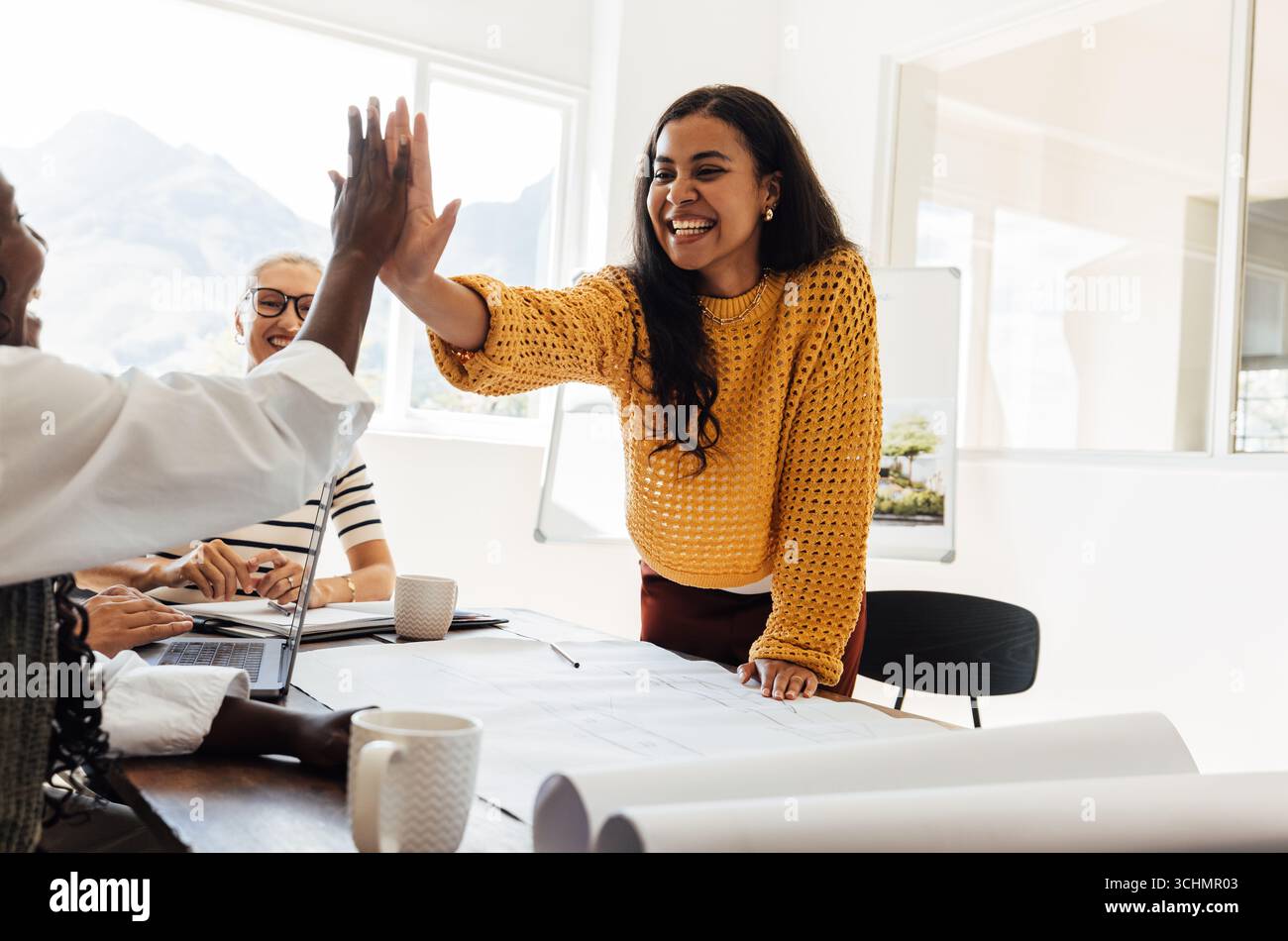 Giovani professionisti che celebrano il successo attraverso il lavoro di squadra e gli alti professionisti in un ambiente d'ufficio. Mostrare il lavoro collaborativo, la creatività e il deposito Foto Stock
