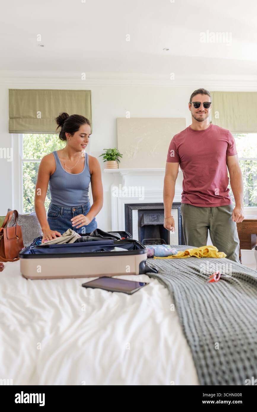 Coppia che prepara la valigia in camera da letto, preparandosi per il viaggio con entusiasmo Foto Stock