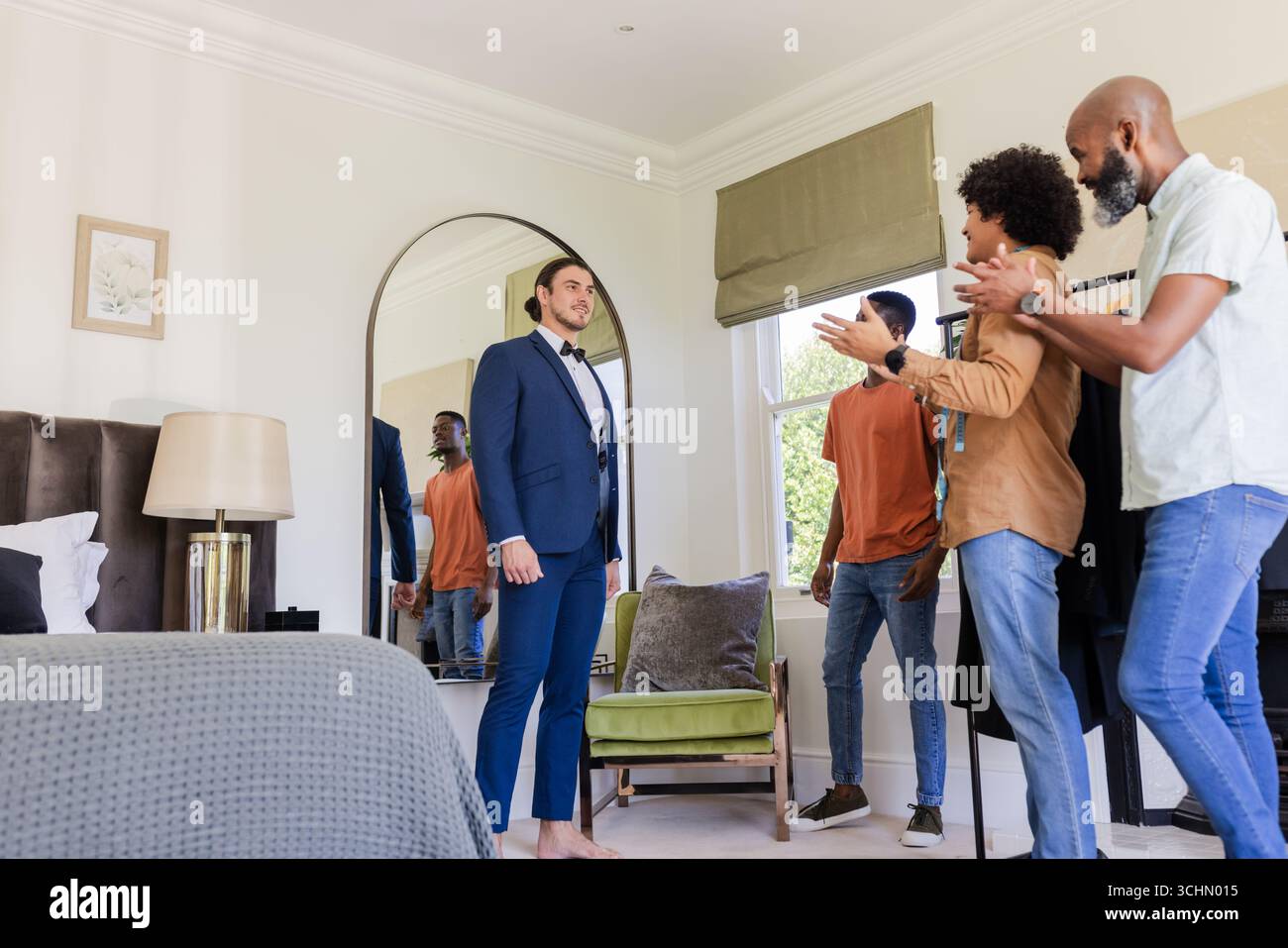 Lo sposo in tuta riceve applausi dagli amici in camera da letto prima della cerimonia nuziale Foto Stock