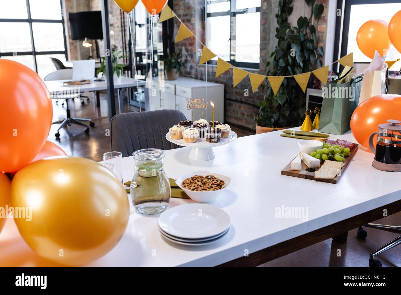 Festeggiare in ufficio con cupcake, palloncini e spuntini sul tavolo, atmosfera festosa Foto Stock