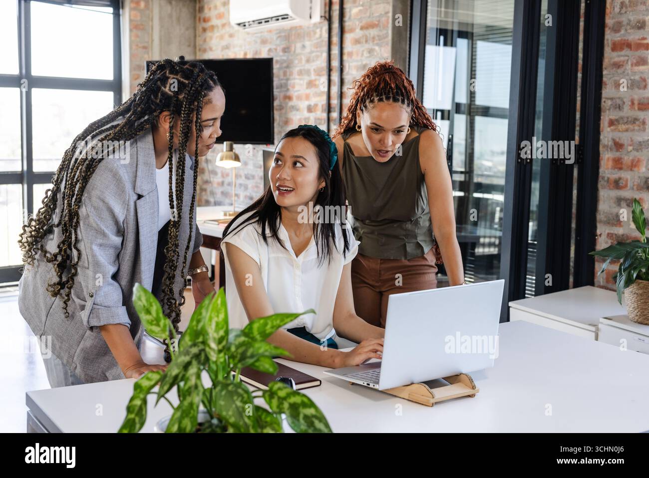 Collaborando in ufficio, diverse donne condividono con entusiasmo idee sui notebook Foto Stock