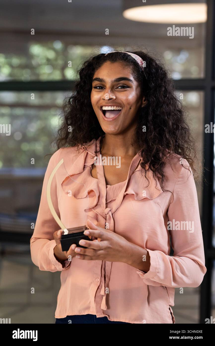 In carica, donna che detiene un premio, celebra con sorriso i risultati professionali Foto Stock