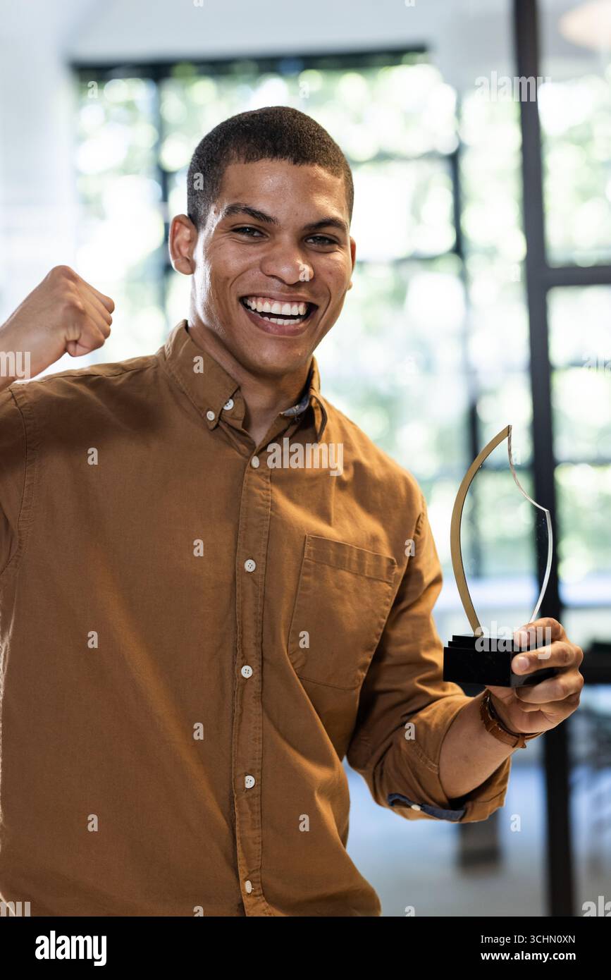 uomo che celebra il successo che tiene il premio in un ufficio moderno Foto Stock