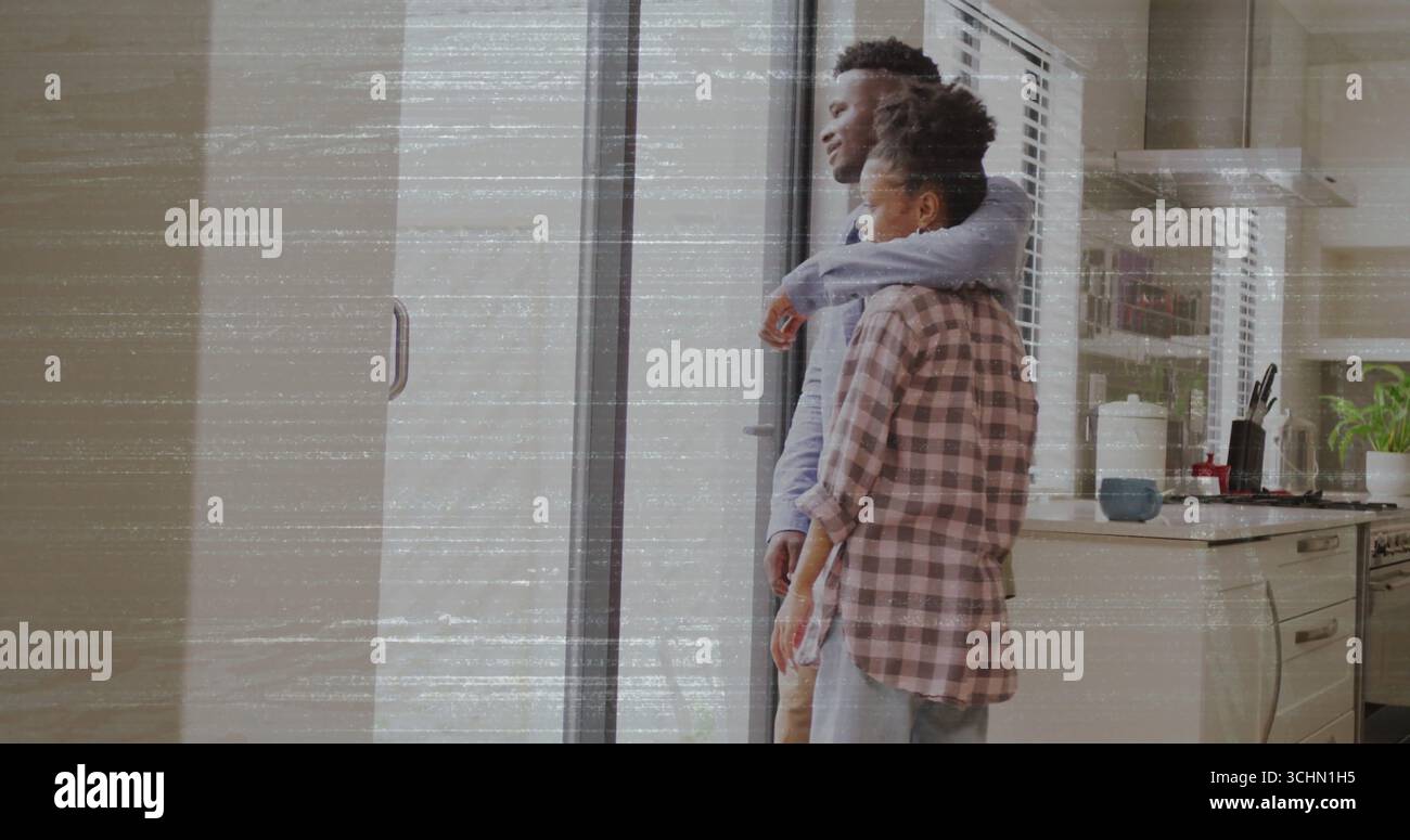 Abbracciando la coppia che guarda attraverso la porta scorrevole in vetro in cucina con utensili per piante da tazza e spazio per copiare Foto Stock
