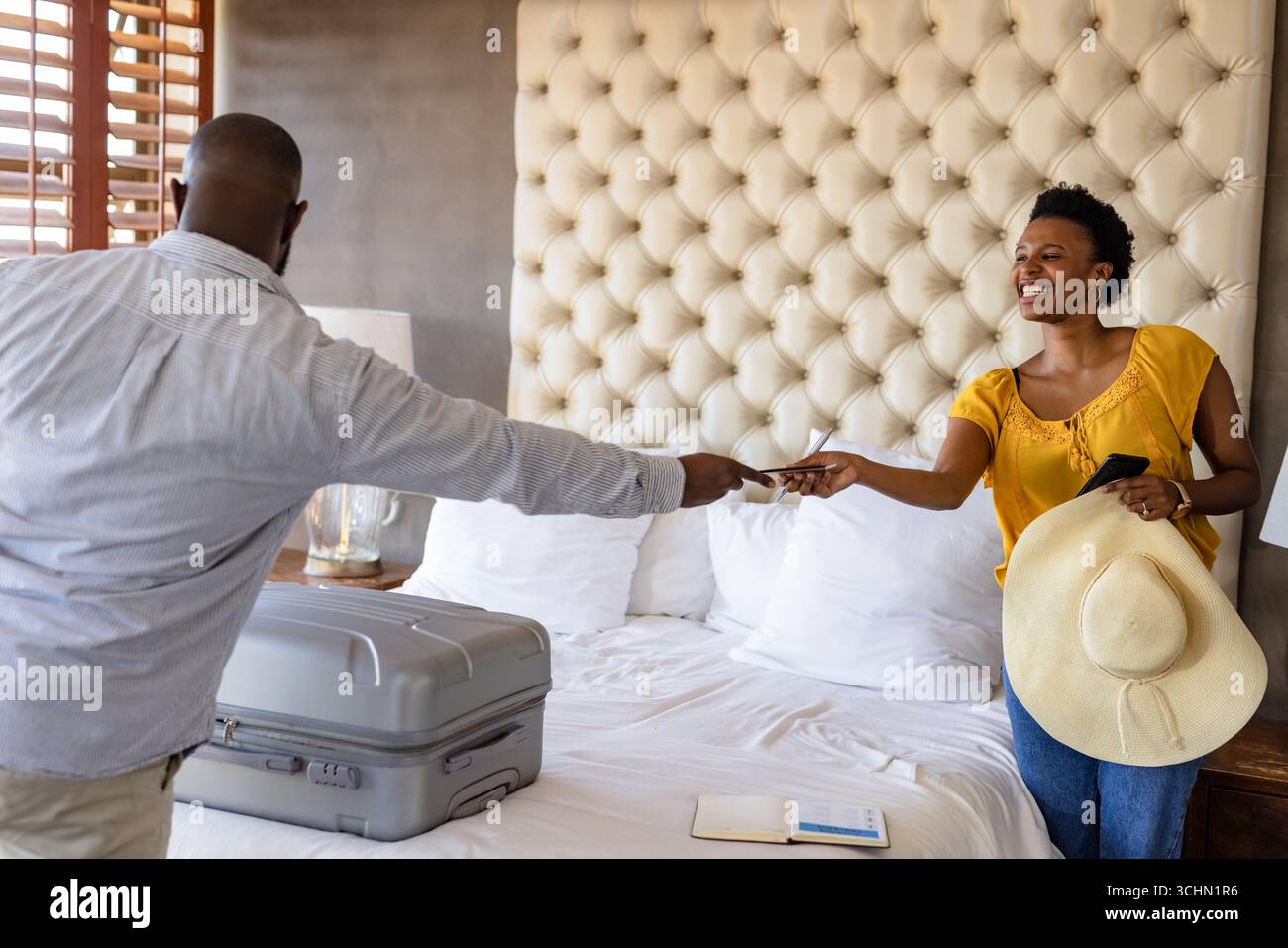 Coppia in camera d'albergo scambiandosi documenti di viaggio, sorridendo e preparandosi per le vacanze Foto Stock
