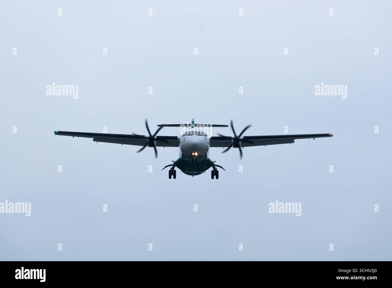 Un velivolo turboelica ATR 72 in avvicinamento finale per atterrare contro un cielo grigio e coperto. Foto Stock