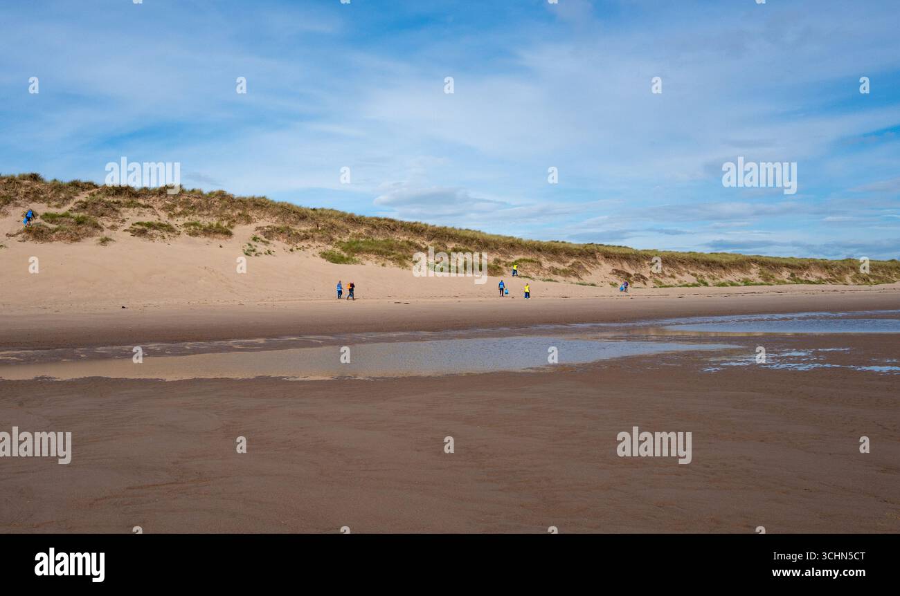 Un gruppo di raccoglitori di rifiuti che si offrono volontari per ripulire la spiaggia lungo la costa a Druridge Bay, Northumberland. Foto Stock