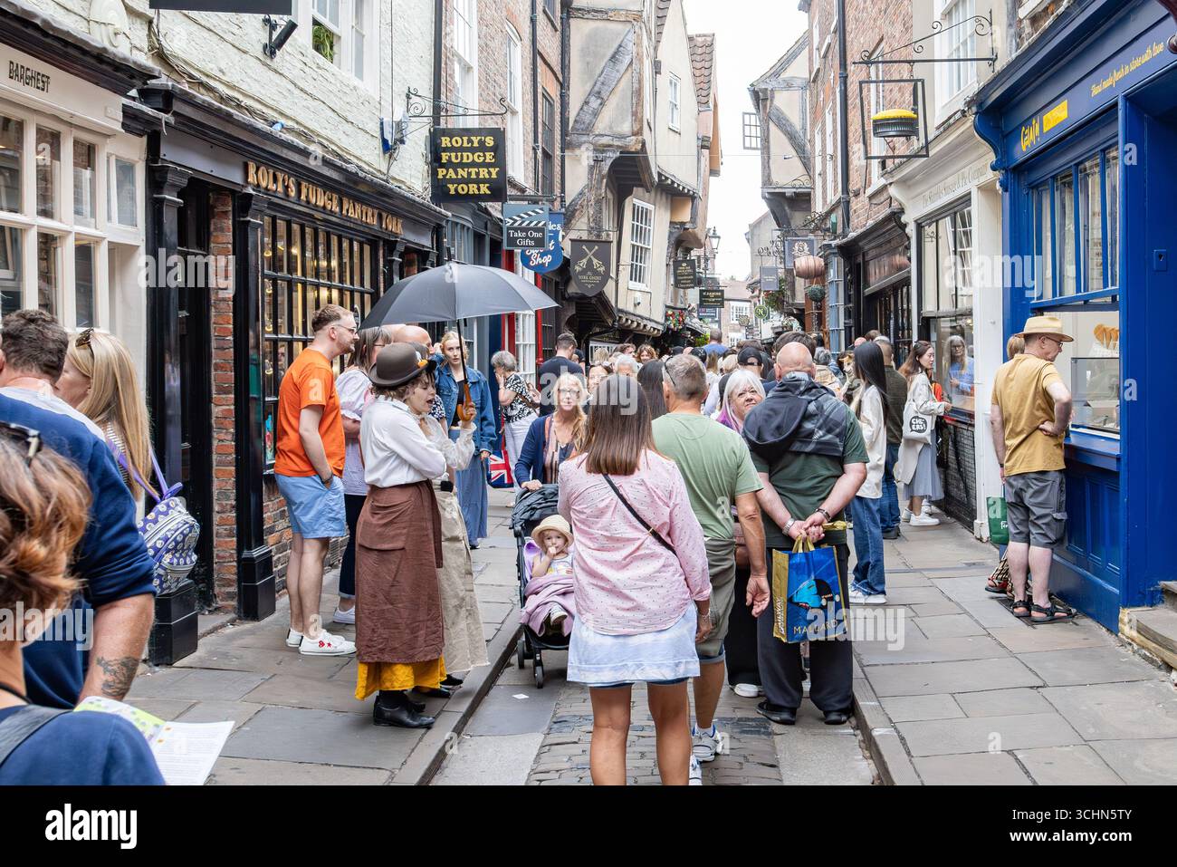 Turisti e locali a Shambles, York, Inghilterra, con edifici in legno, fascino storico e attività promozionali fuori dalla Fudge Pantry di Roly. Foto Stock