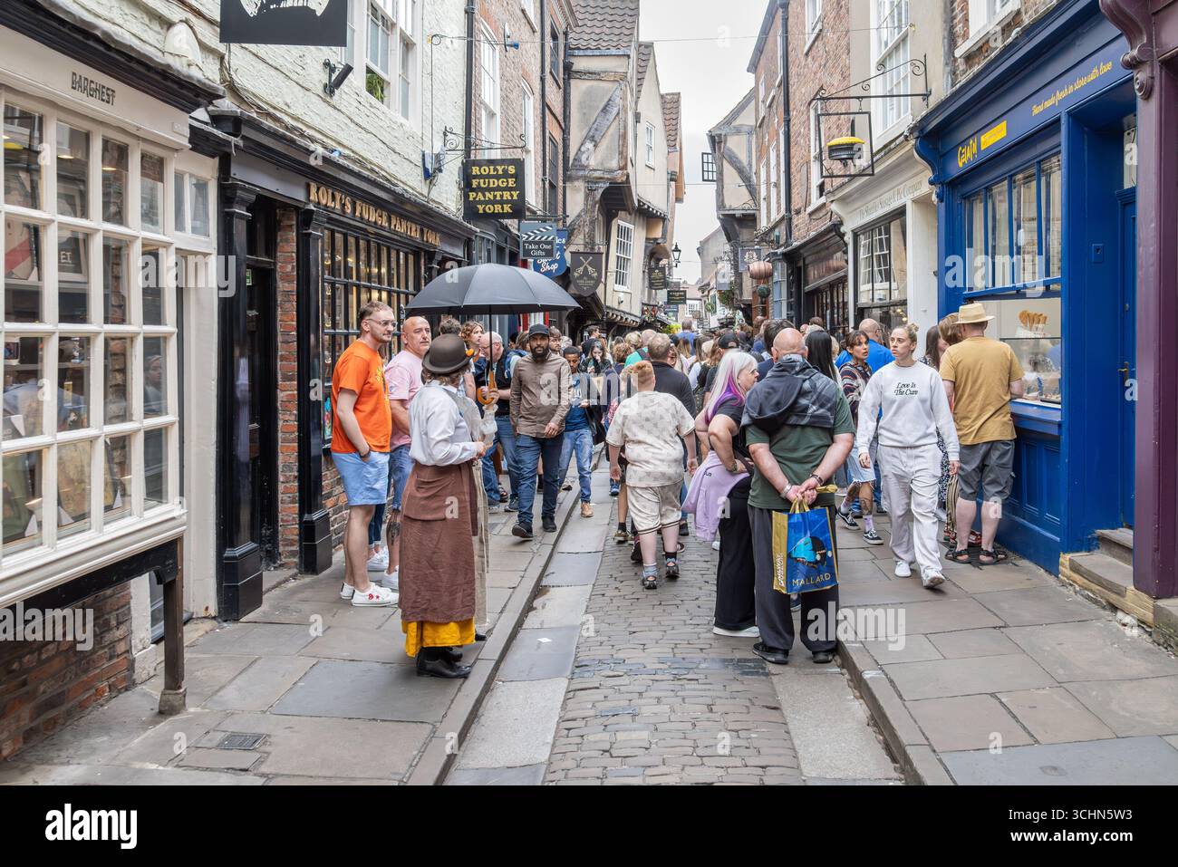 Turisti e locali a Shambles, York, Inghilterra, con edifici in legno, fascino storico e attività promozionali fuori dalla Fudge Pantry di Roly. Foto Stock
