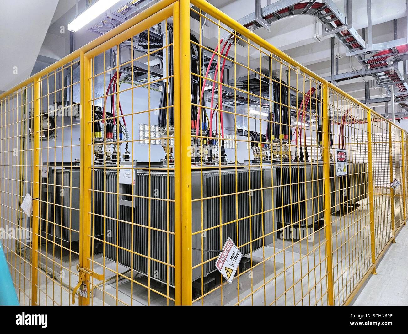Sistema di trasformatori elettrici racchiuso in gabbia protettiva, installazione di sicurezza industriale in impianti elettrici. Bandung, Indonesia - 17 gennaio 2024 - Immagine stock catturata con smartphone