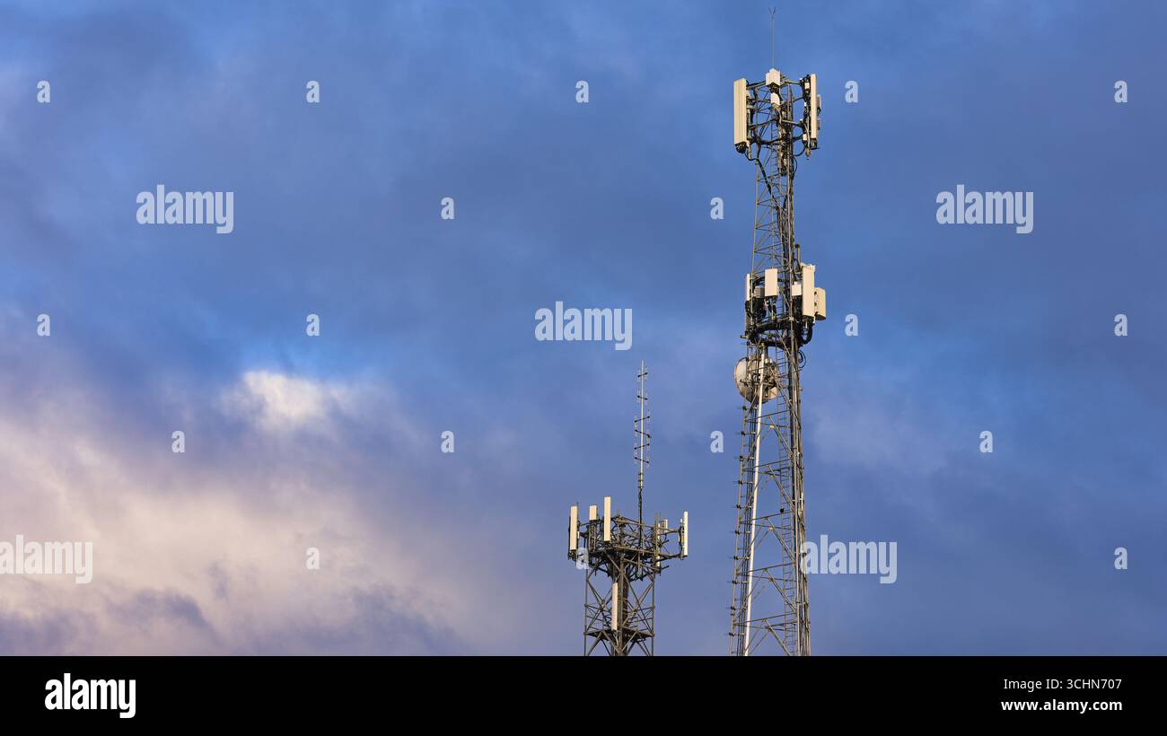 Due torri di comunicazione mobile catturate sotto livelli di nuvole mostruose Foto Stock