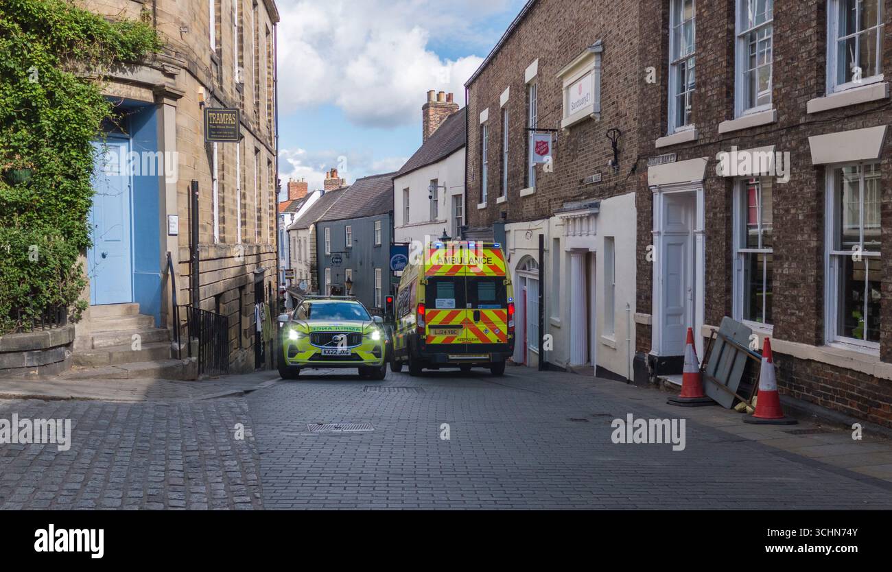 Due veicoli di emergenza ambulanza con luci blu visibili che trattano di incidente di emergenza in Saddler Street, Durham, Inghilterra, Regno Unito Foto Stock