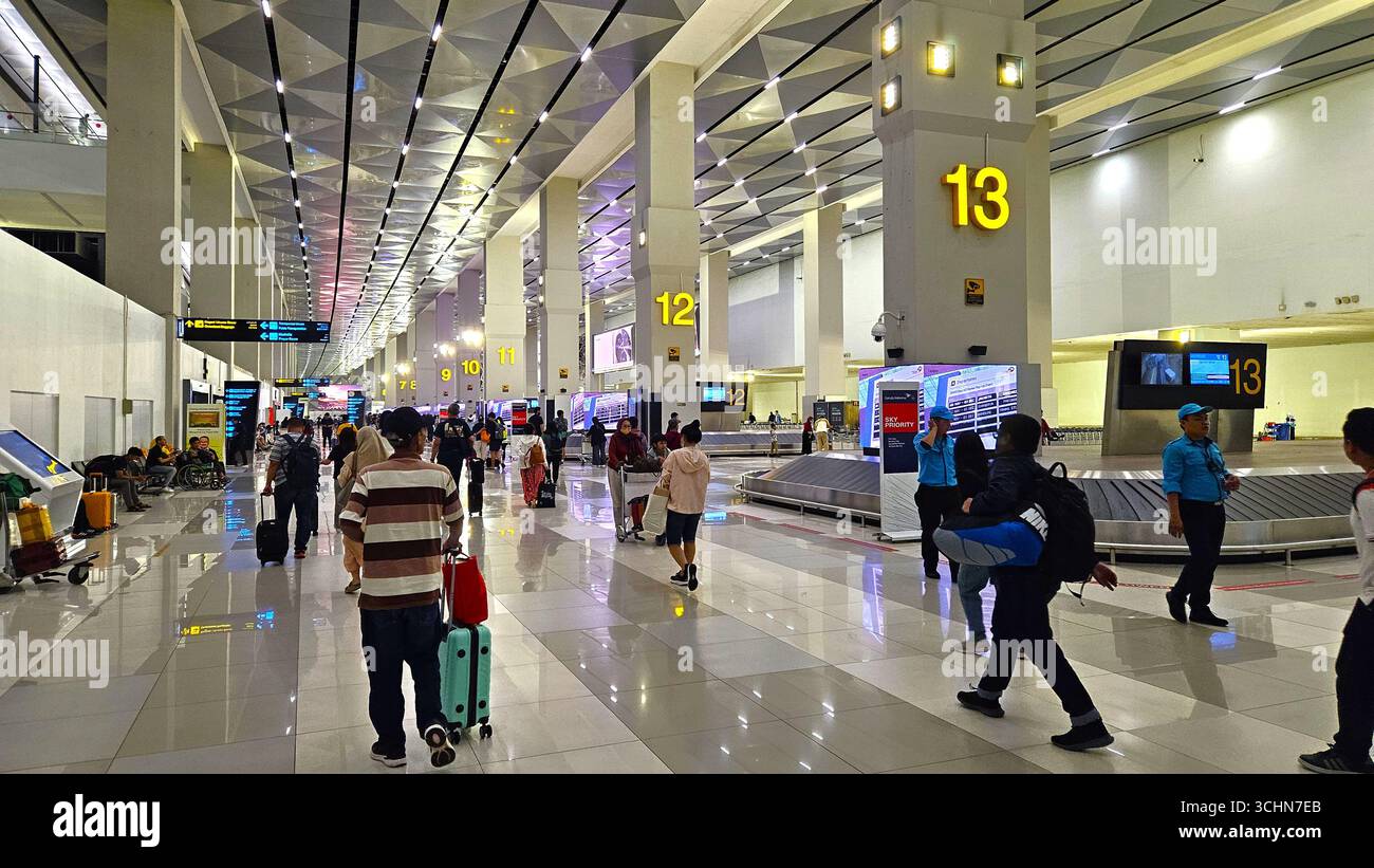 Terminal dell'aeroporto affollato con passeggeri che camminano nell'area check-in sotto interni luminosi e moderni. Giacarta, Indonesia - 17 dicembre 2024 - Immagine stock catturata con smartphone