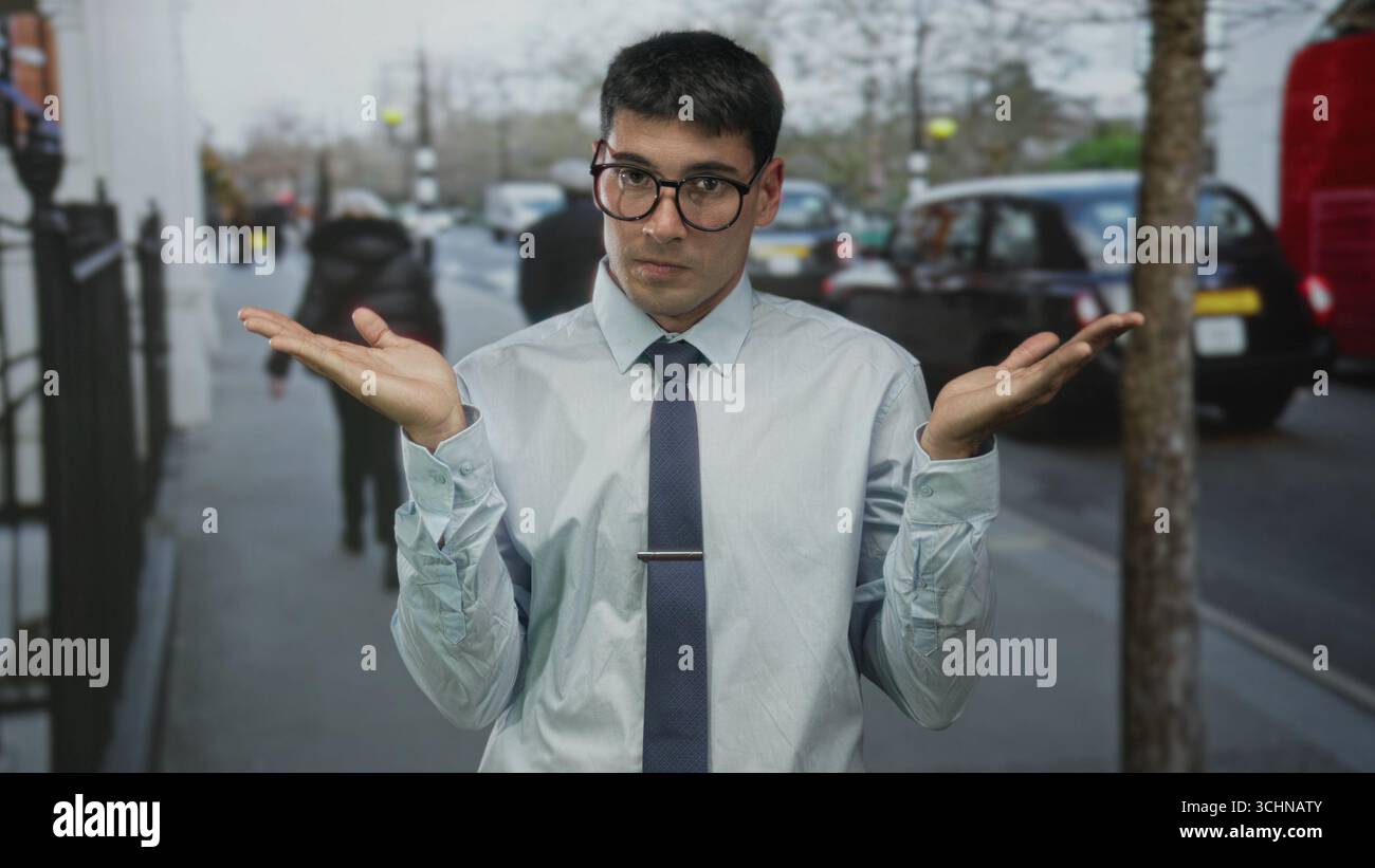 Giovane ispanico con le palme sollevate vicino al taxi parcheggiato sulla strada trafficata della città; confusione dubbio incertezza perplessità. Foto Stock